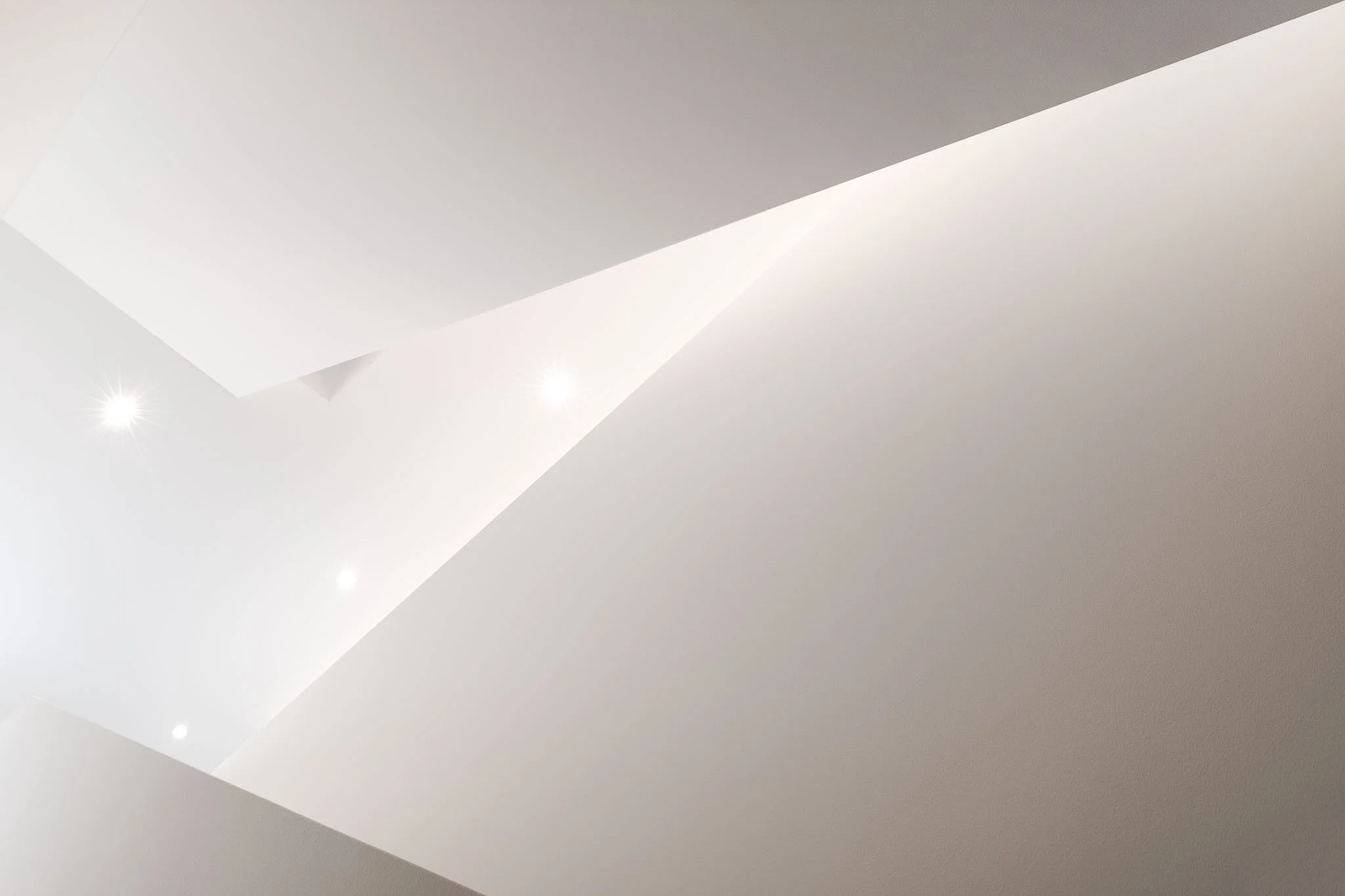 Moderne minimale weisse Deckenleuchte mit integrierter Beleuchtung und sichtbar wirkungsvoller Lichtstrahlung an der Decke.