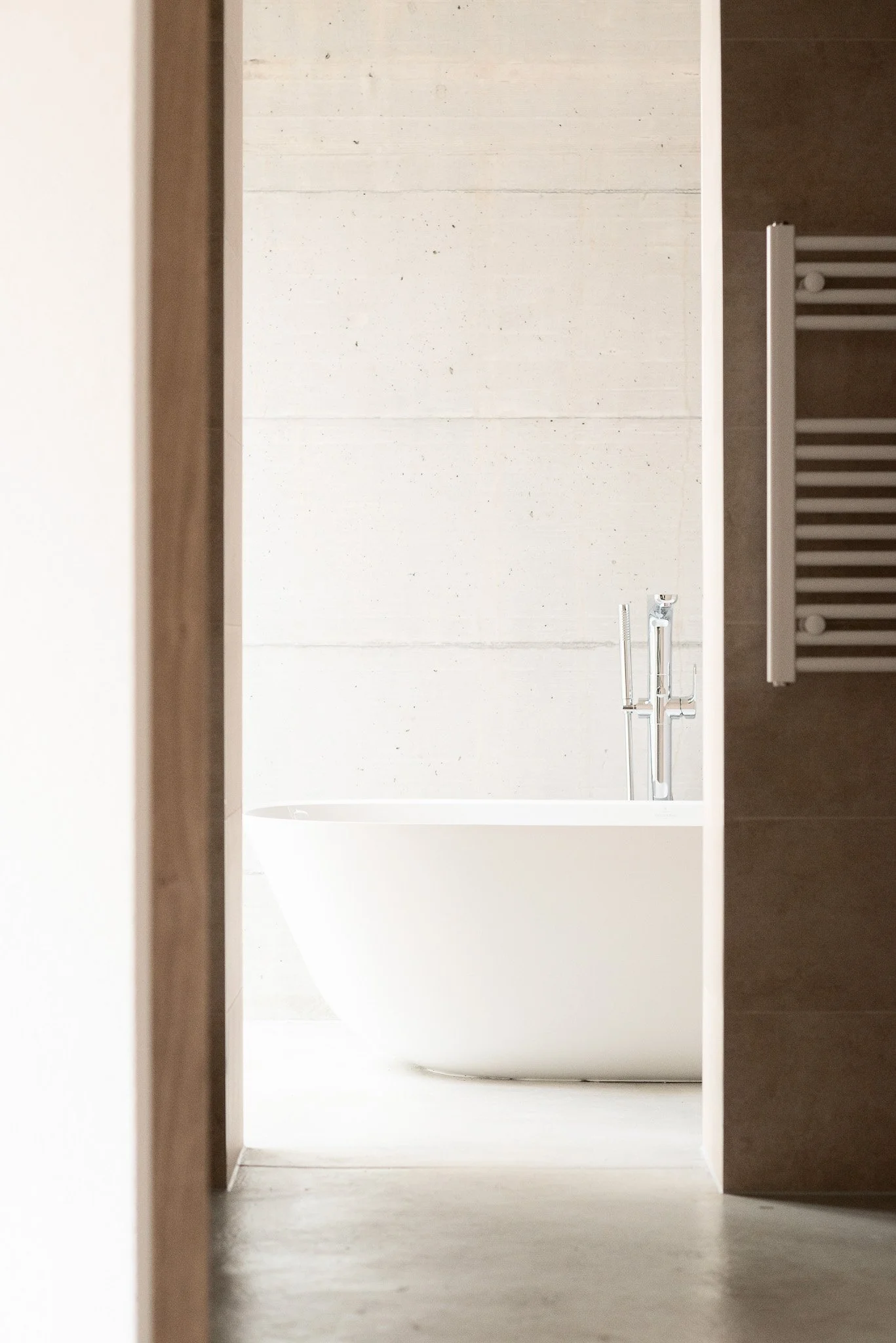 Blick in eine minimalistische, moderne Badezimmer mit weißer Badewanne, Waschtisch und Badezimmerfliesen.