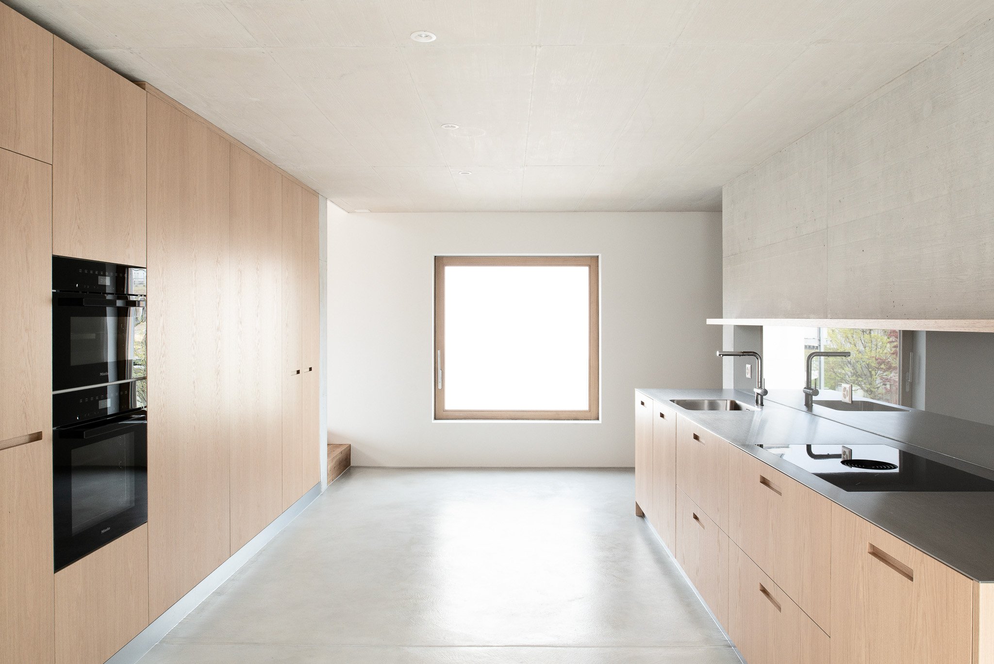 Moderne Küche mit Holzküchenmöbeln, einem grossen Fenster und einer Spüle.