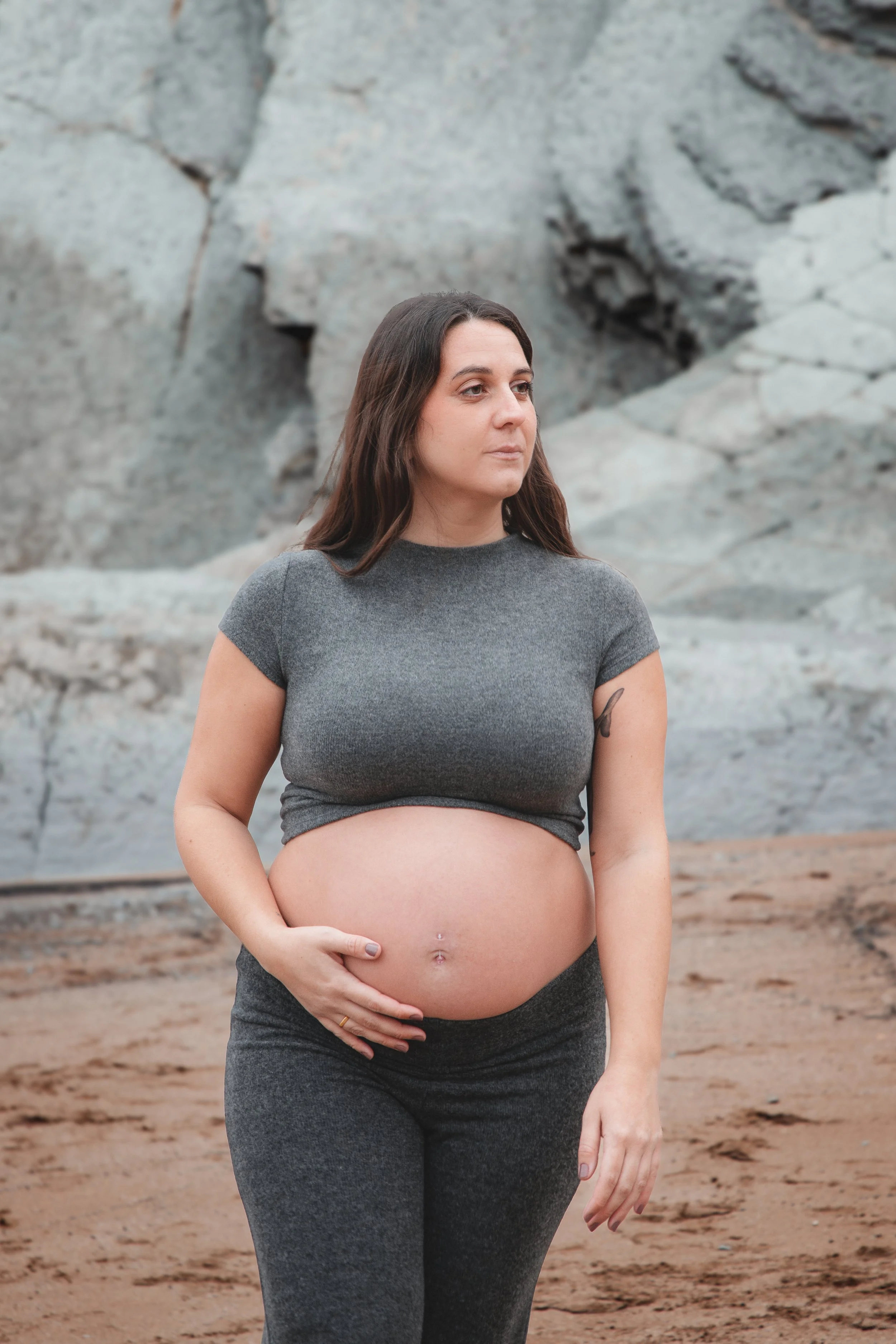 Mujer embarazada en un entorno natural con roca y tierra.