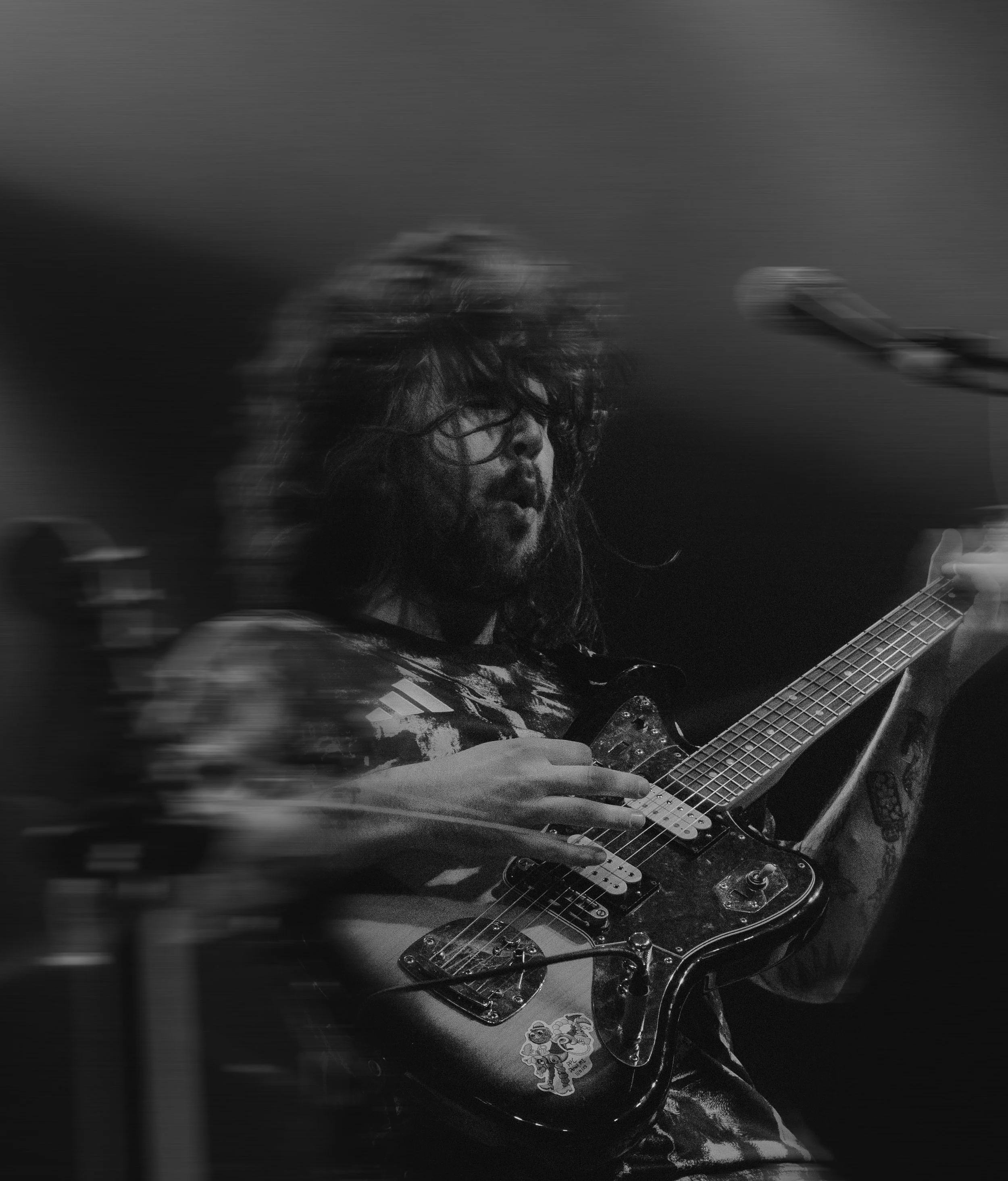 Un músico tocando la guitarra eléctrica en un escenario, con movimiento y desenfoque en un entorno de concierto.