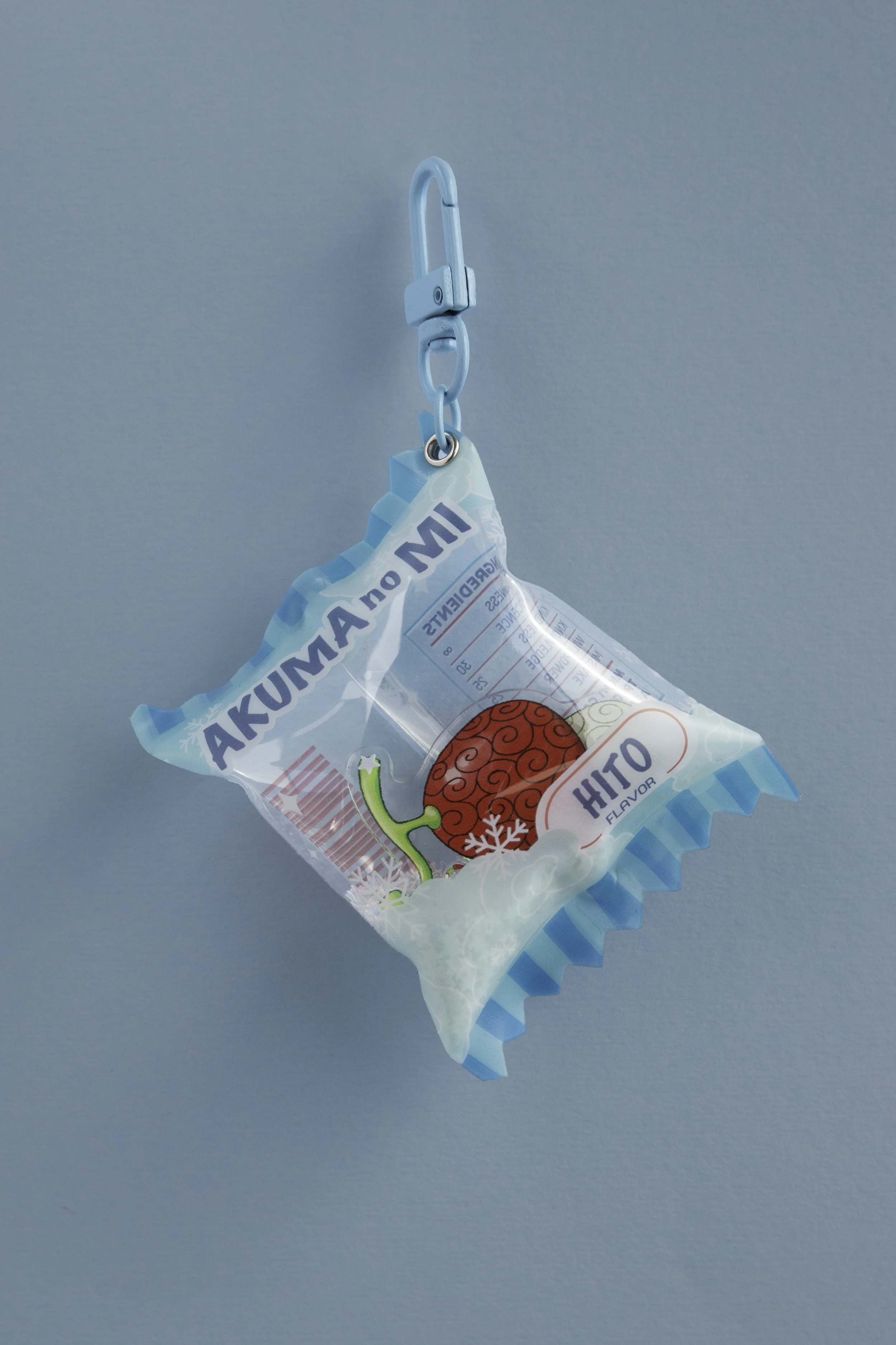 Paquete de hielo con dibujo de una cereza y etiquetas en español, colgado con un clip de plástico azul.