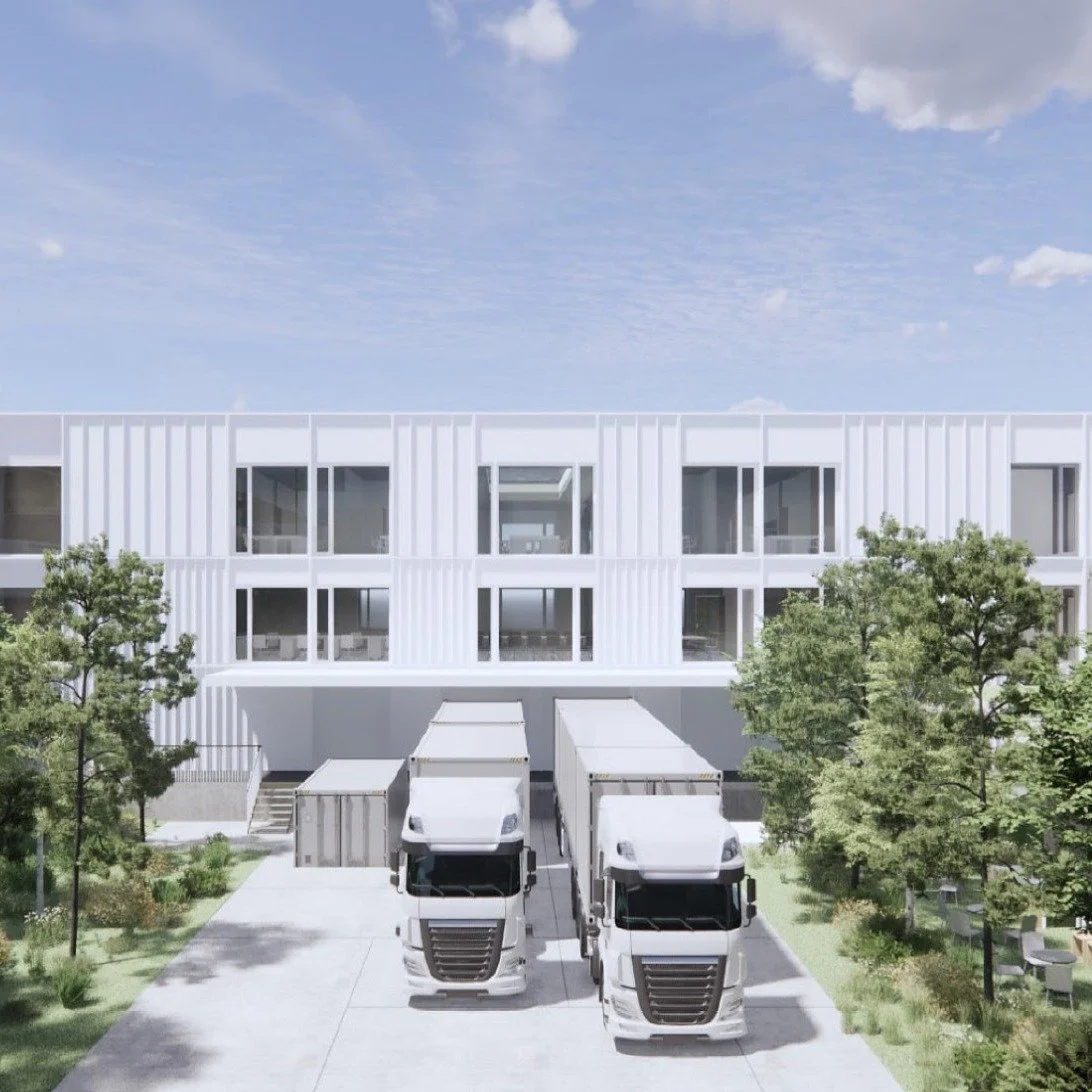 Moderne weiße Wohnanlage mit mehreren Reihen von Fenstern, vor der Gebäude ein Parkplatz mit zwei weißen LKWs und Bäumen auf beiden Seiten.