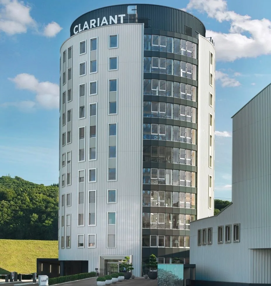 Ein modernes, hohes Bürogebäude mit runden Formen und großen Fenstern, darüber die Aufschrift "CLARIANT".