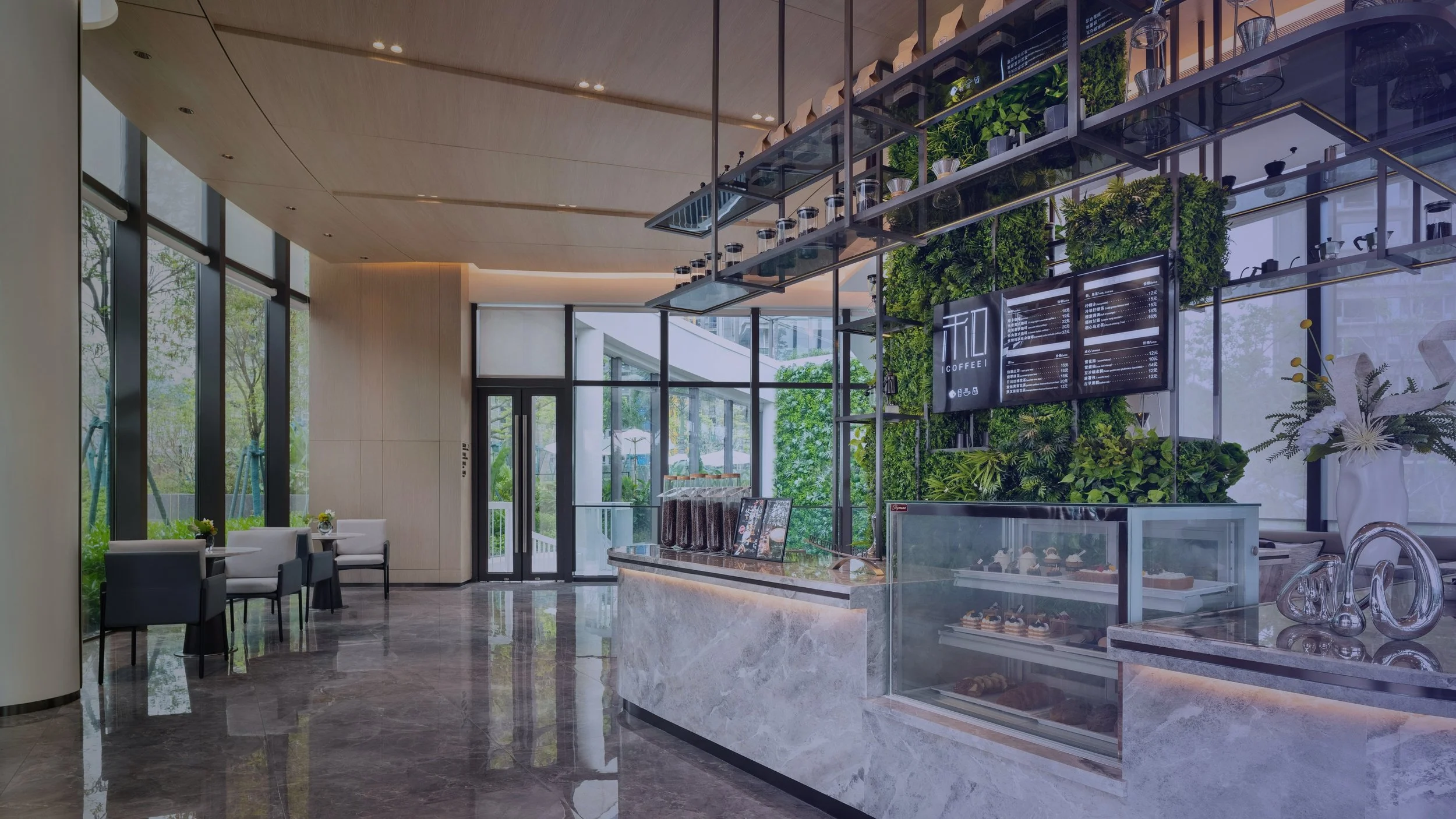 Interior of a modern coffee shop with large windows, a green wall, a menu board, and seating area.