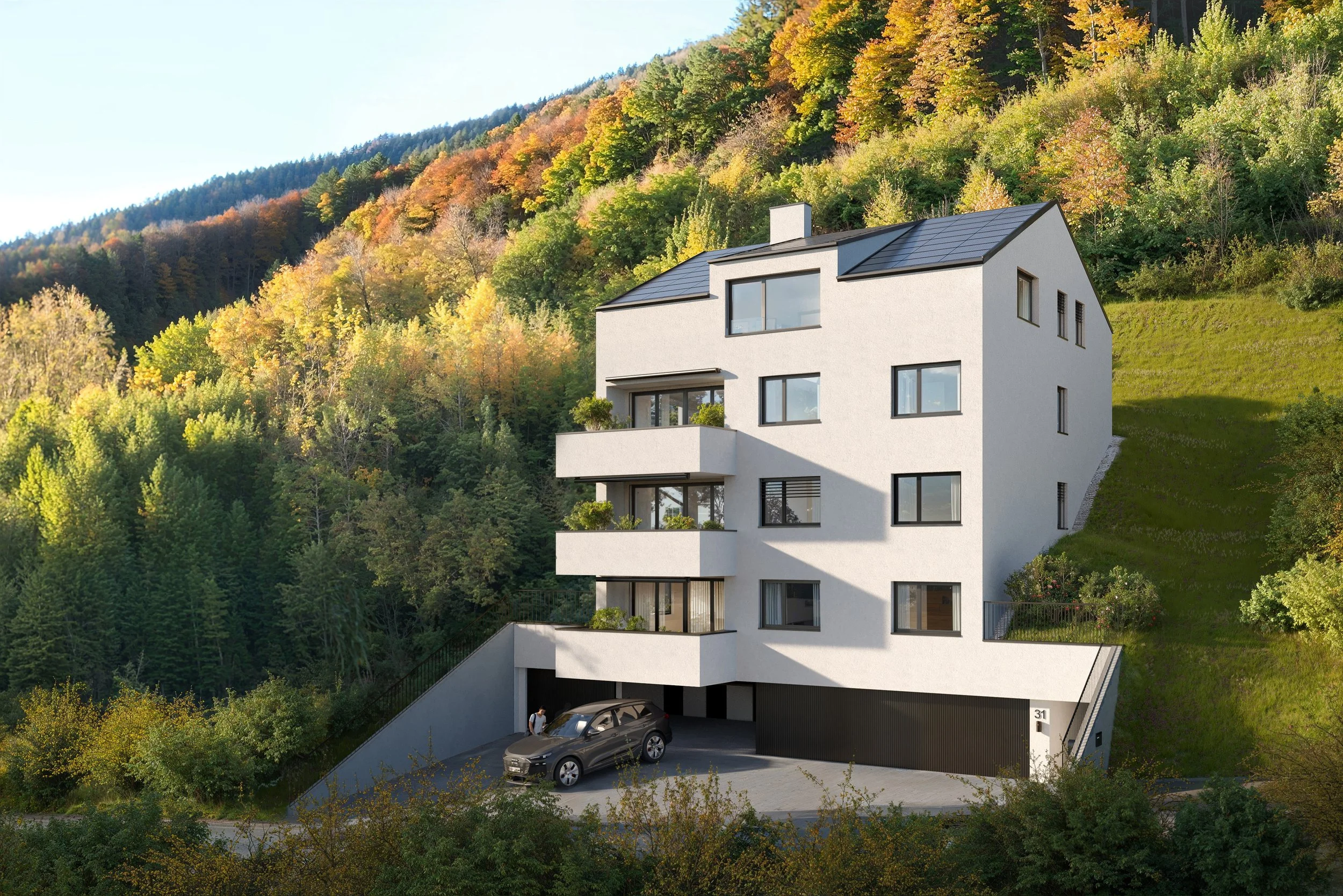 Modernes weißes Mehrfamilienhaus an einem Hang inmitten eines bewaldeten Gebietes mit Herbstfärbung, mit mehreren Balkonen, Garage und parkendem Auto.