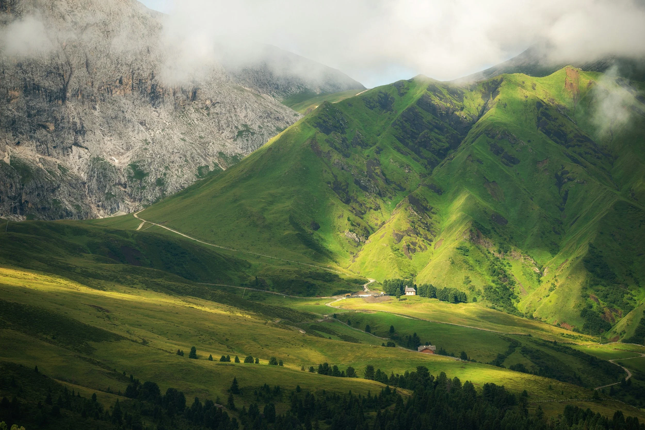 Blick über grüne Hänge in die umliegende Bergwelt