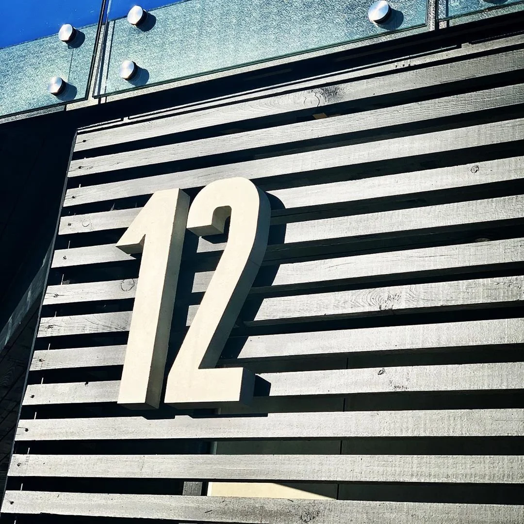 Talonumero 12 mustassa teräksessä vaakasuuntaisella metallipaneelijulkisivulla