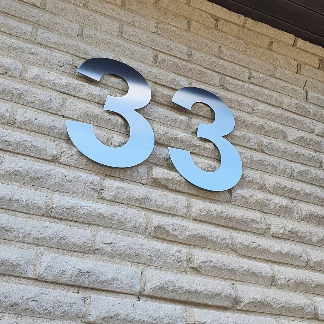 Talonumero 33 harjatussa ruostumattomassa teräksessä karkealla kivimuuri