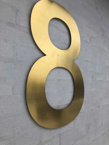 Suuri talonumero 8 messingistä – lähikuva kiillotetusta kultapinnasta