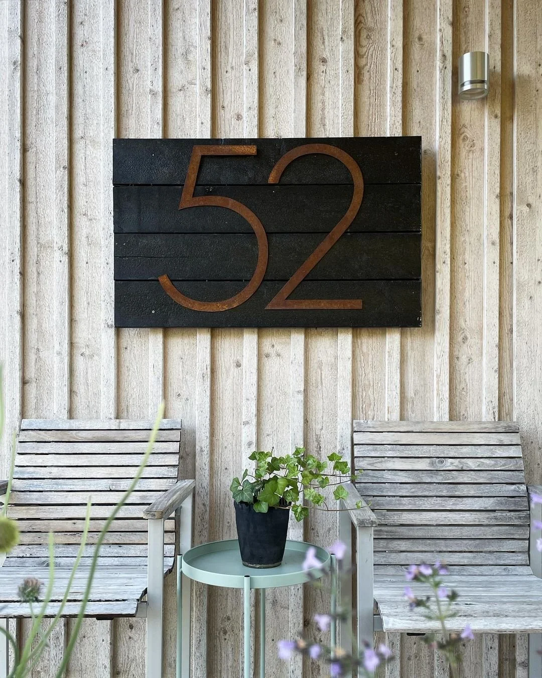 Corten-teräksinen talonumero 52 mustalla puutaustalla