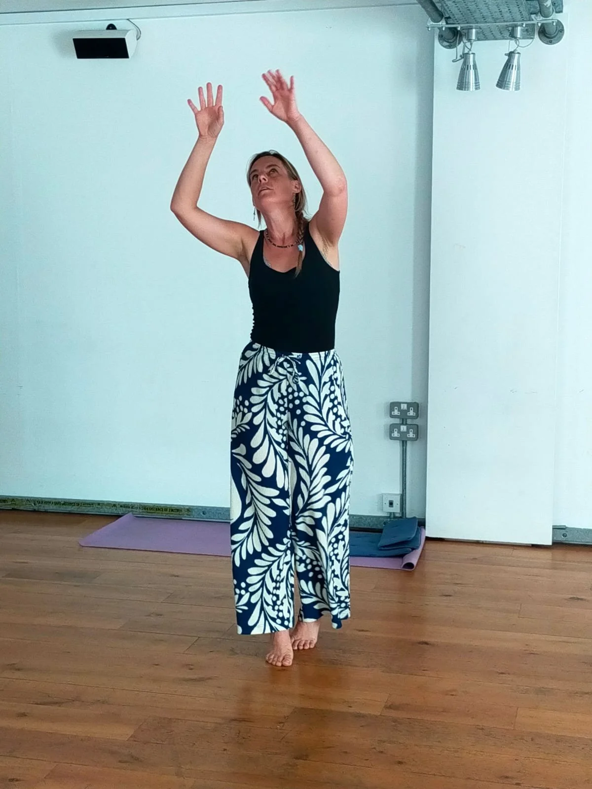 Mareike moving barefoot in a movement studio, arms raised overhead, during a Dance Movement Psychotherapy session