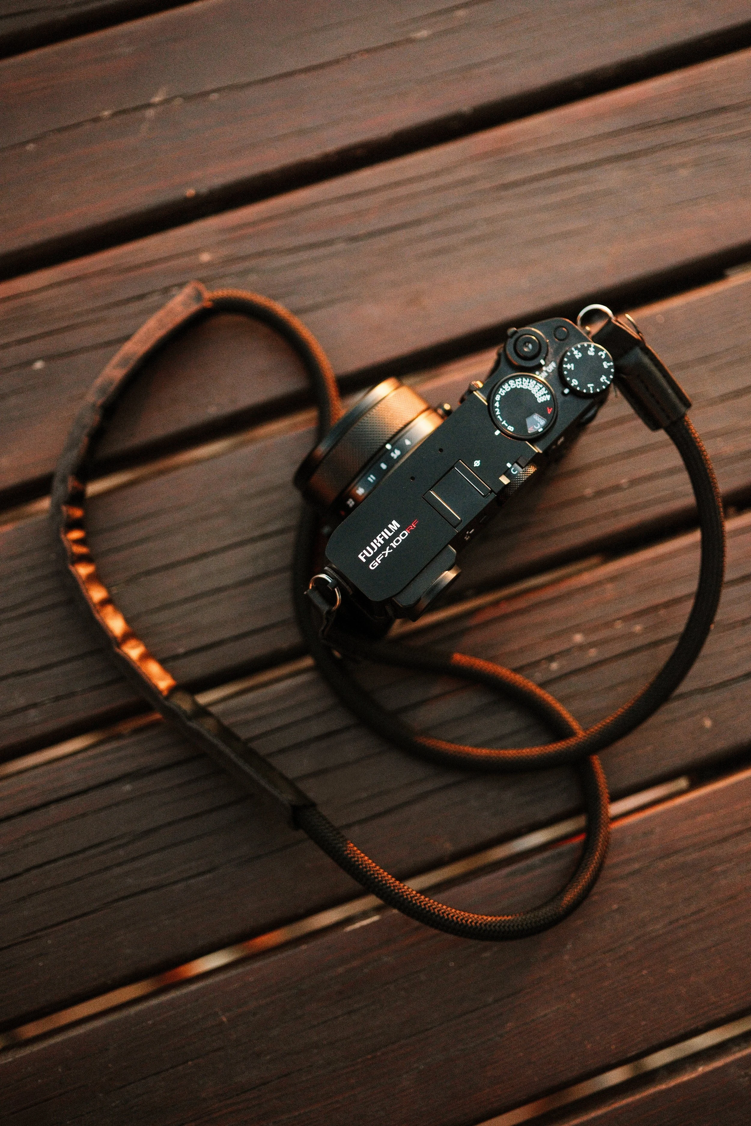 A black Fujifilm camera with a strap, placed on a wooden surface.