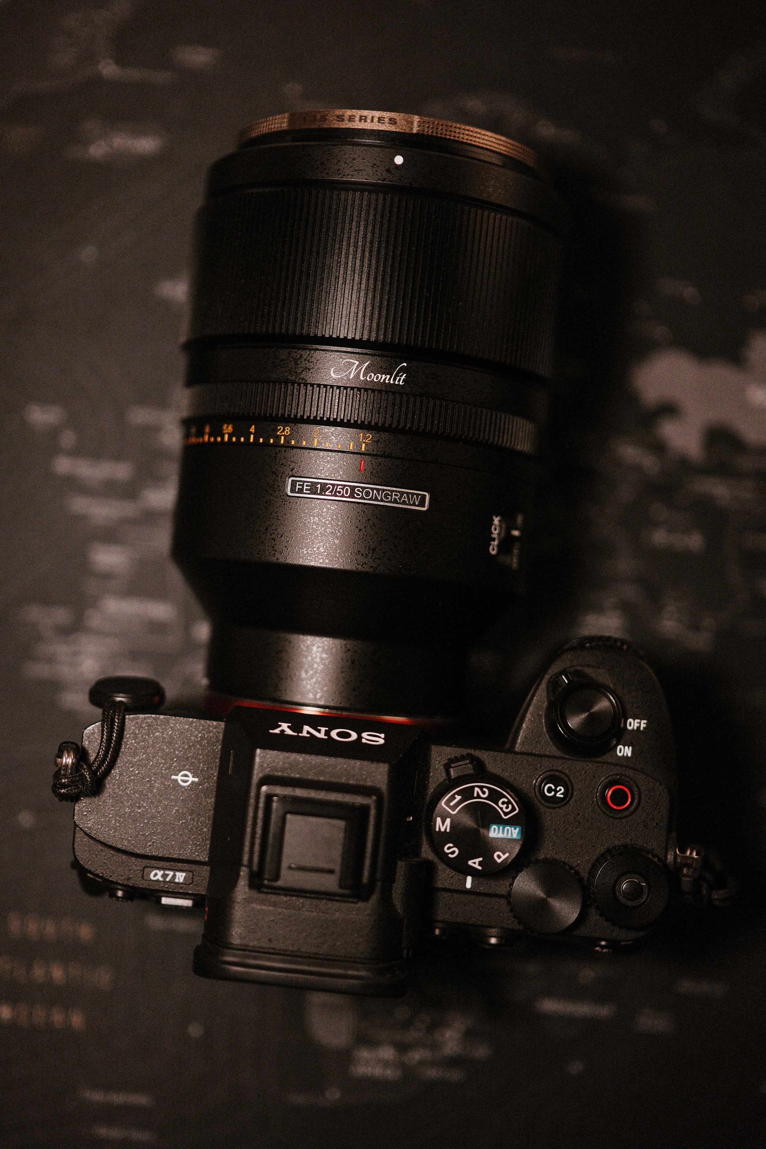 A Sony mirrorless camera with a mounted large lens, photographed from above against a dark background.