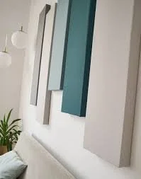 Decorative wall art with elongated rectangular panels in shades of gray, white, and teal above a white sofa and a potted plant.