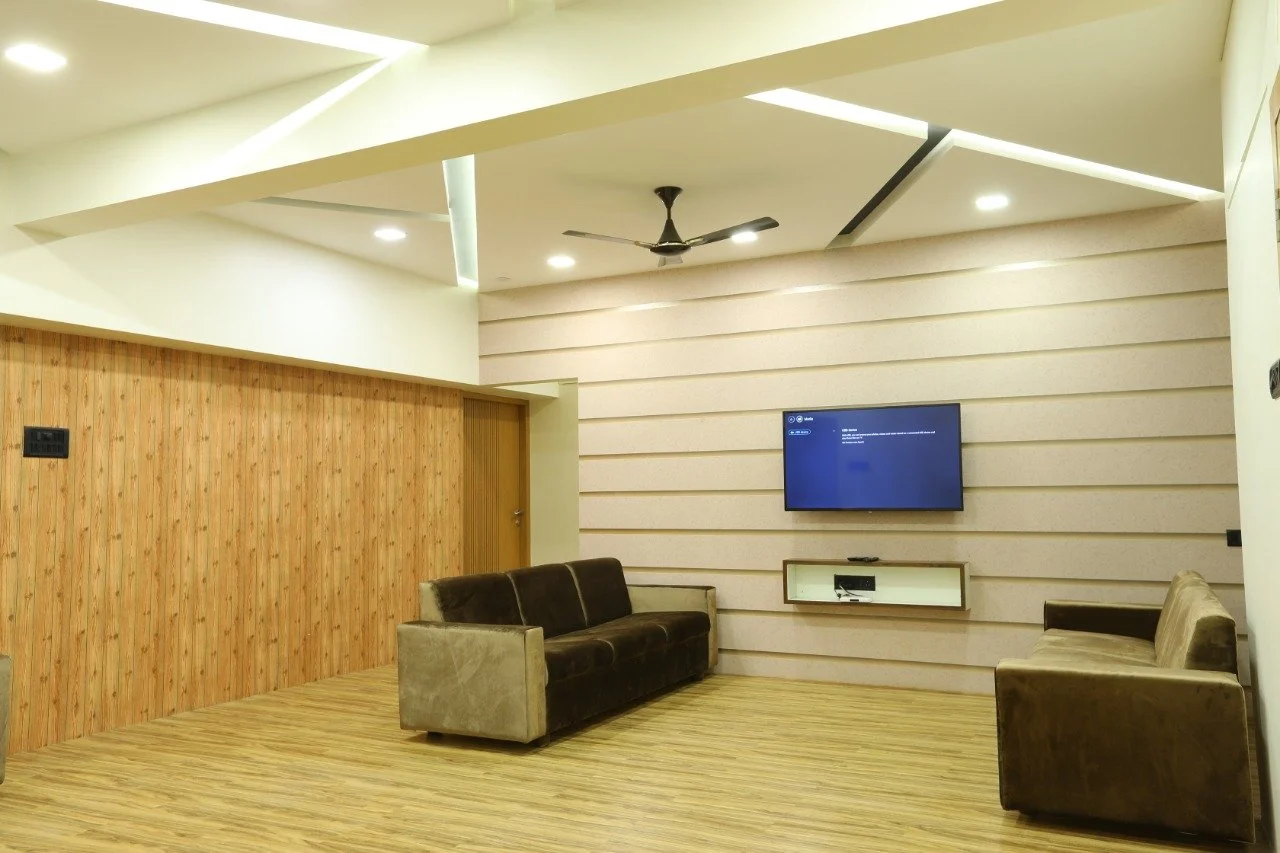 Modern living room with two sofas, a wall-mounted TV, and wooden and beige panel walls.