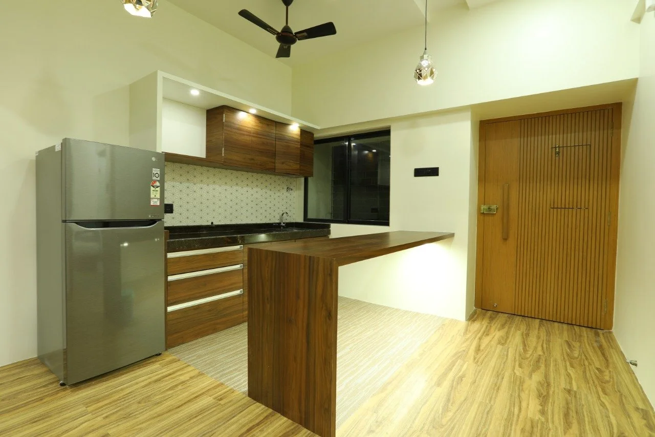 Modern kitchen with wooden cabinets, a refrigerator, a black countertop, and a wooden sliding door.