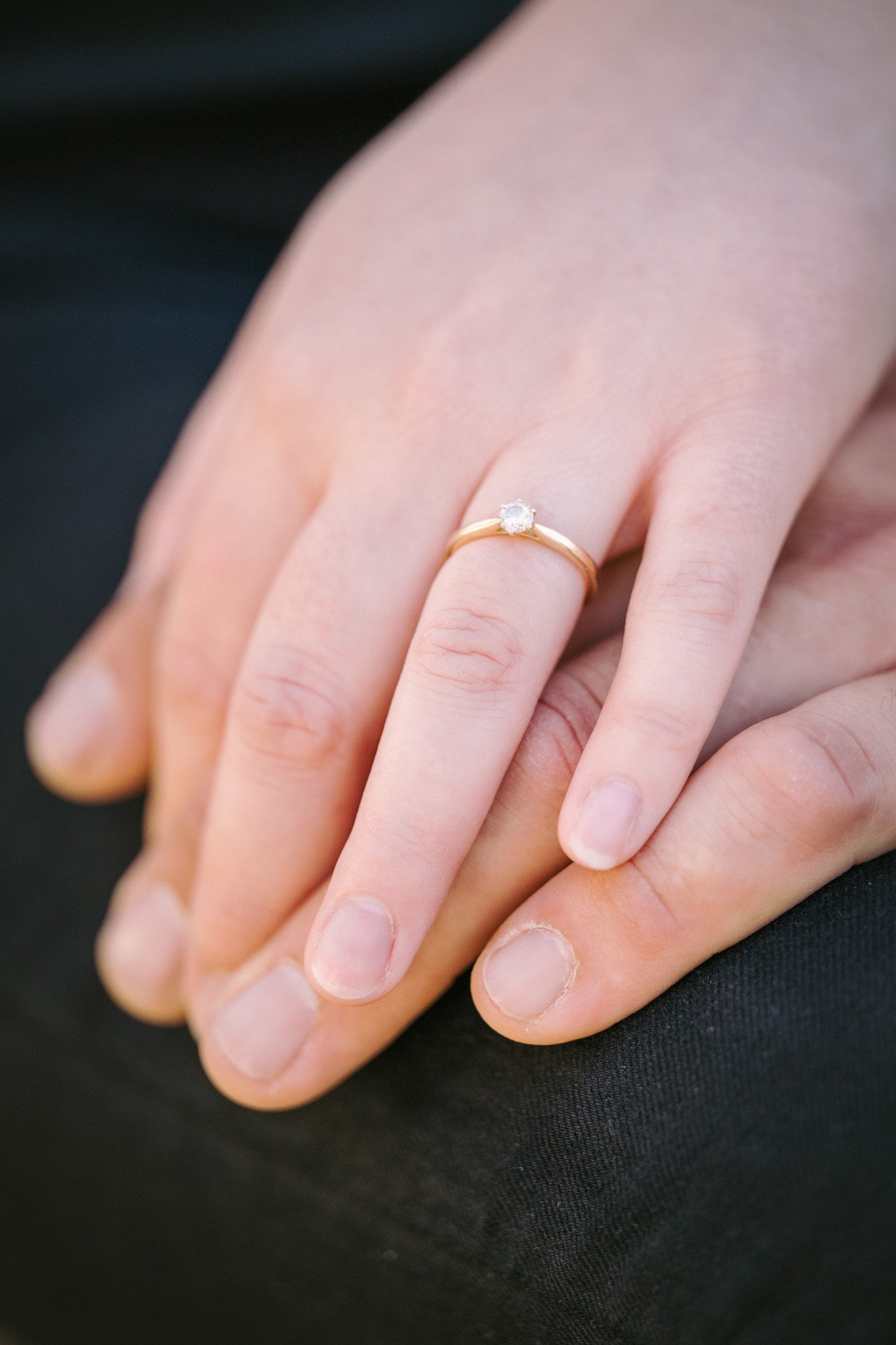 Hand mit einem goldenen Ring mit einem Diamanten an der Ringfinger.