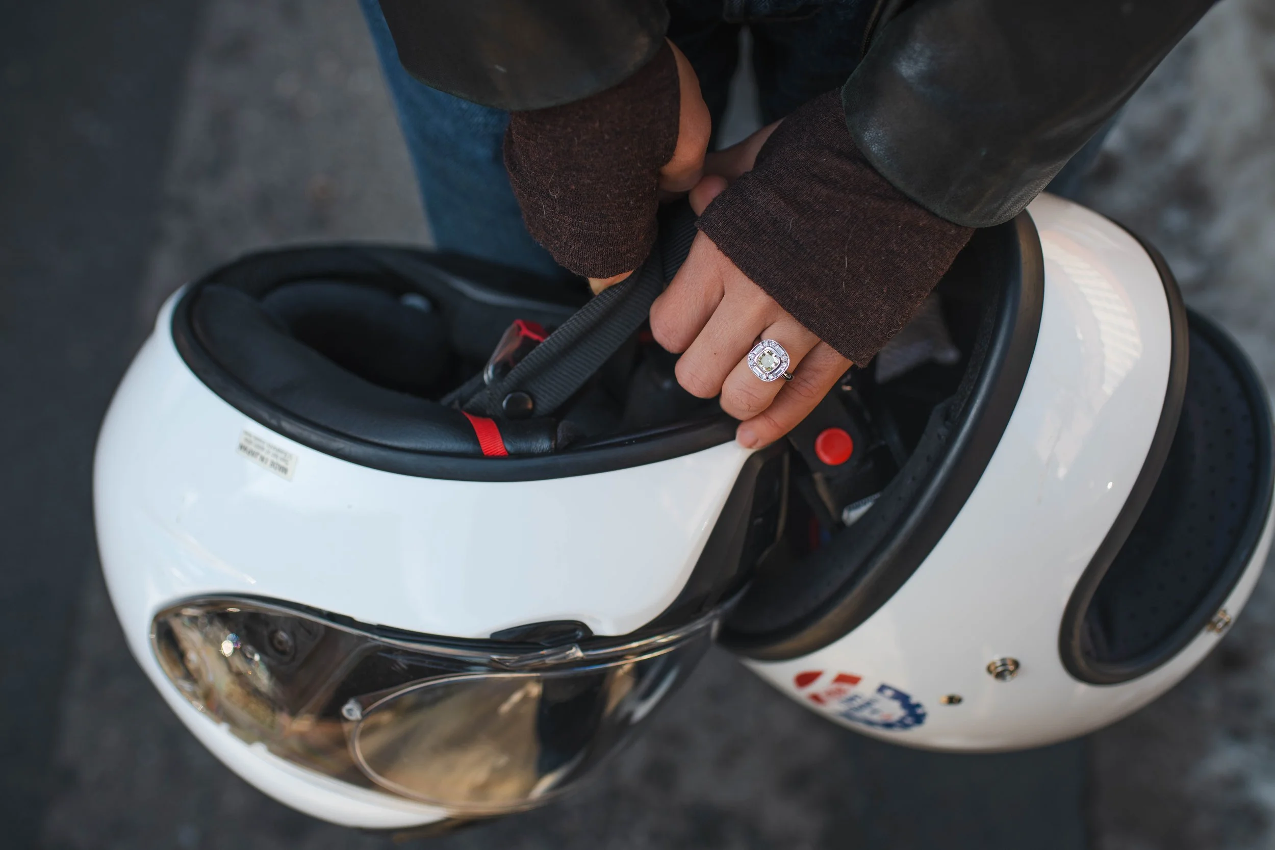 Engagement ring detail shot held alongside motorcycle helmets during a Brooklyn at-home engagement session