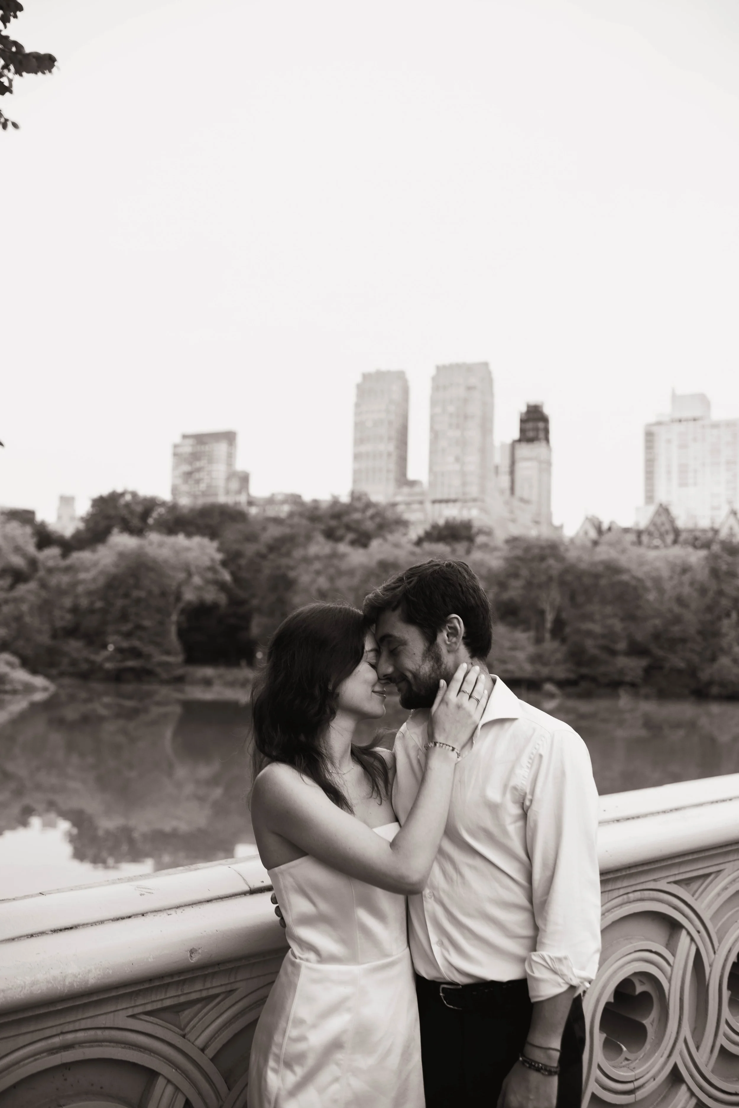 Couple embracing on Bow Bridge during a Central Park engagement session in NYC