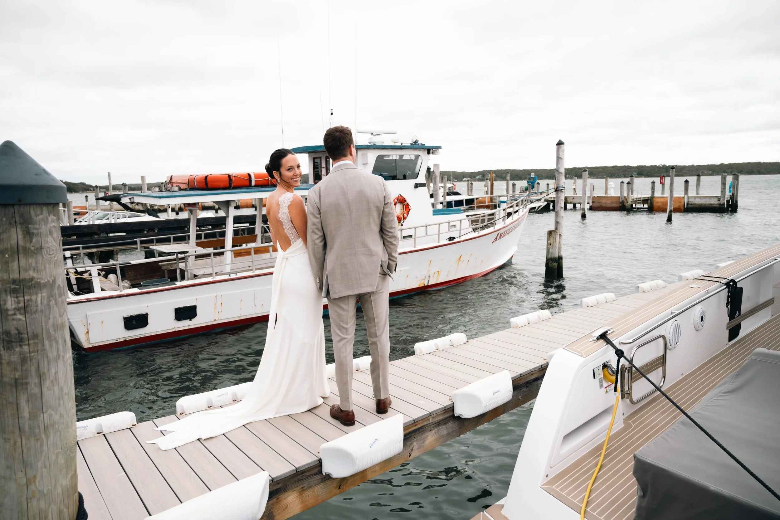An editorial portrait of the newlyweds standing on a waterfront boat dock during a coastal East Hampton wedding.