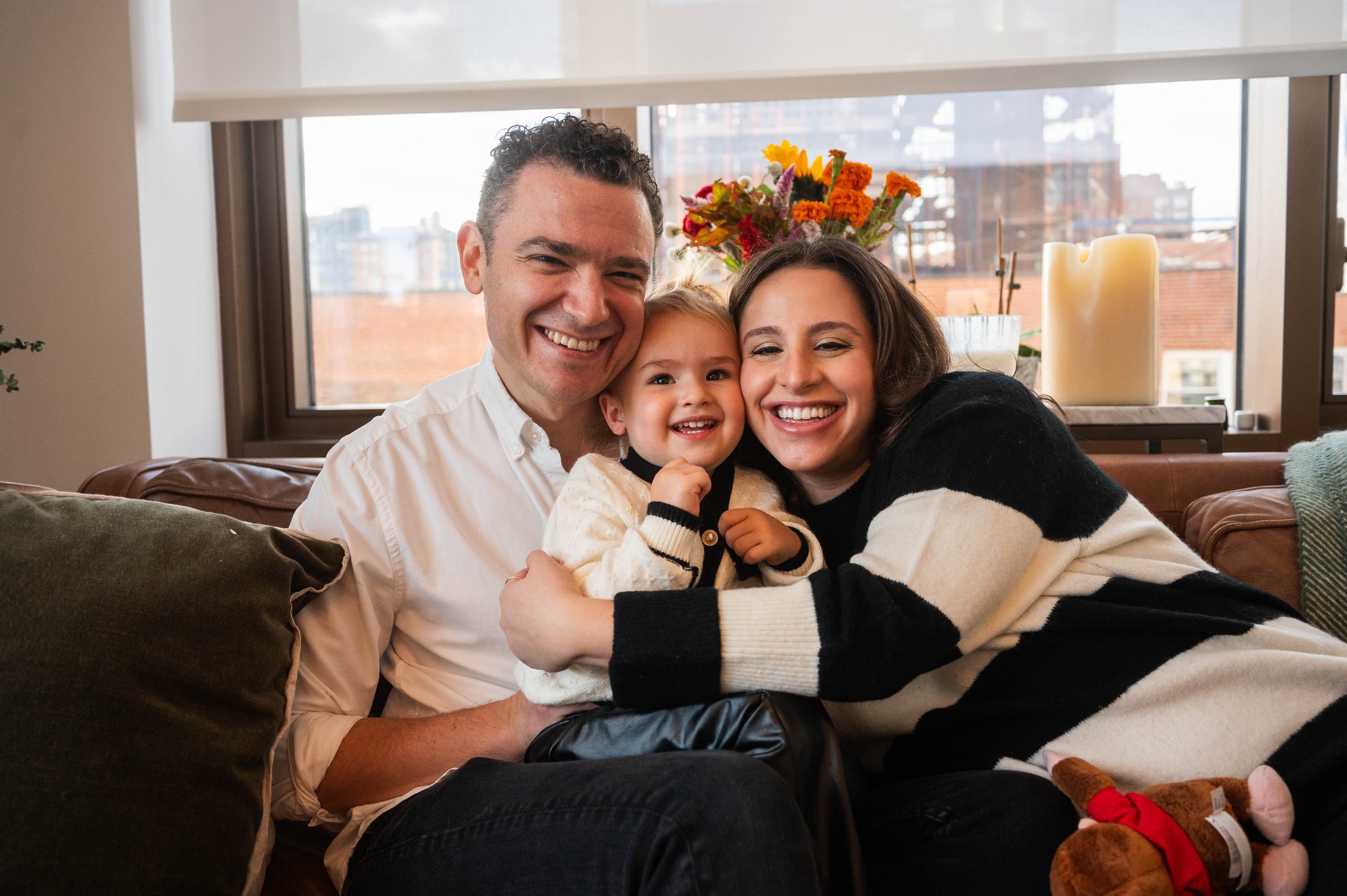 Family smiling together on their couch during an in-home family portrait session in Kips Bay Manhattan