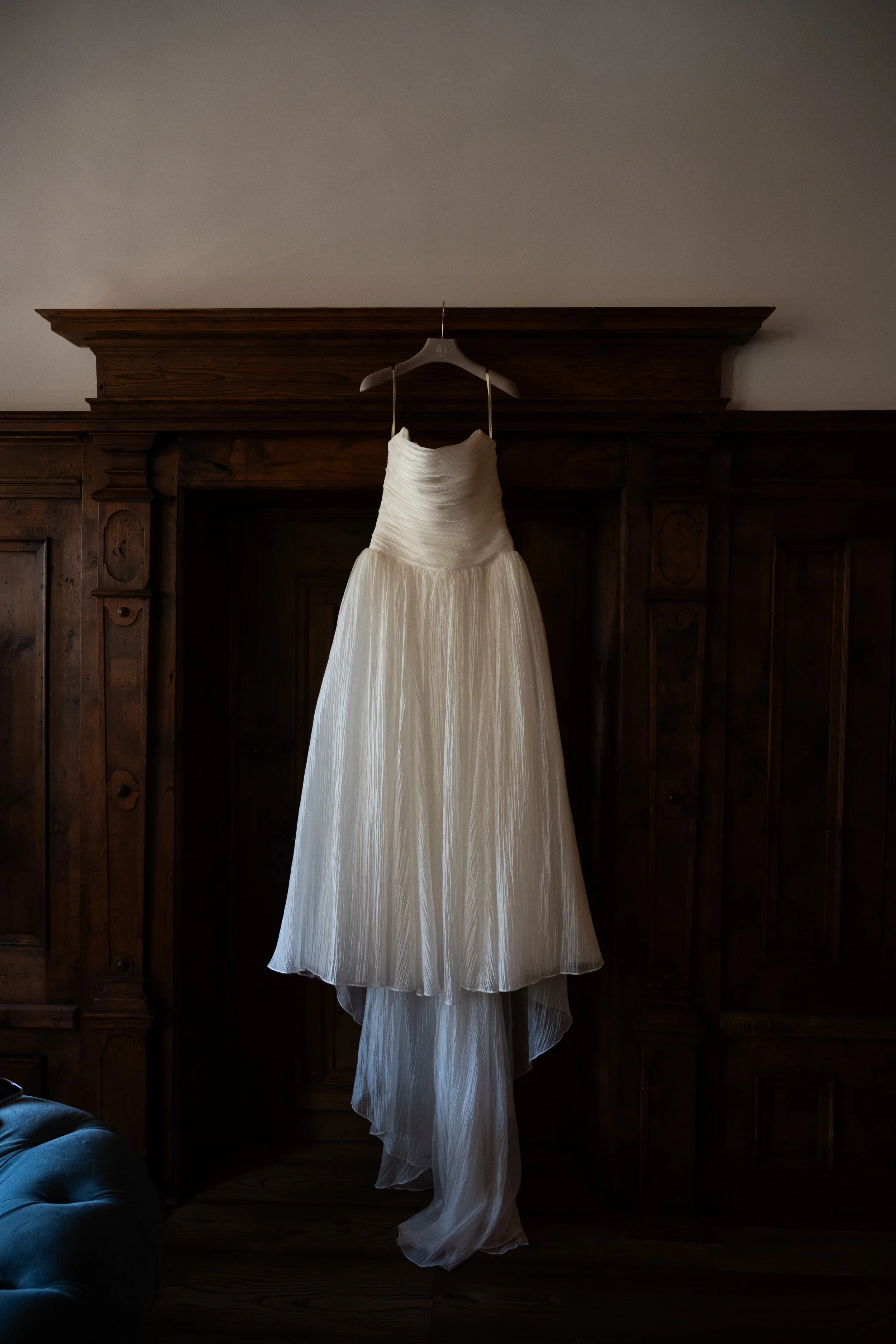  Designer wedding dress displayed hanging in a classic historic doorway inside Castel Hörtenberg. 
