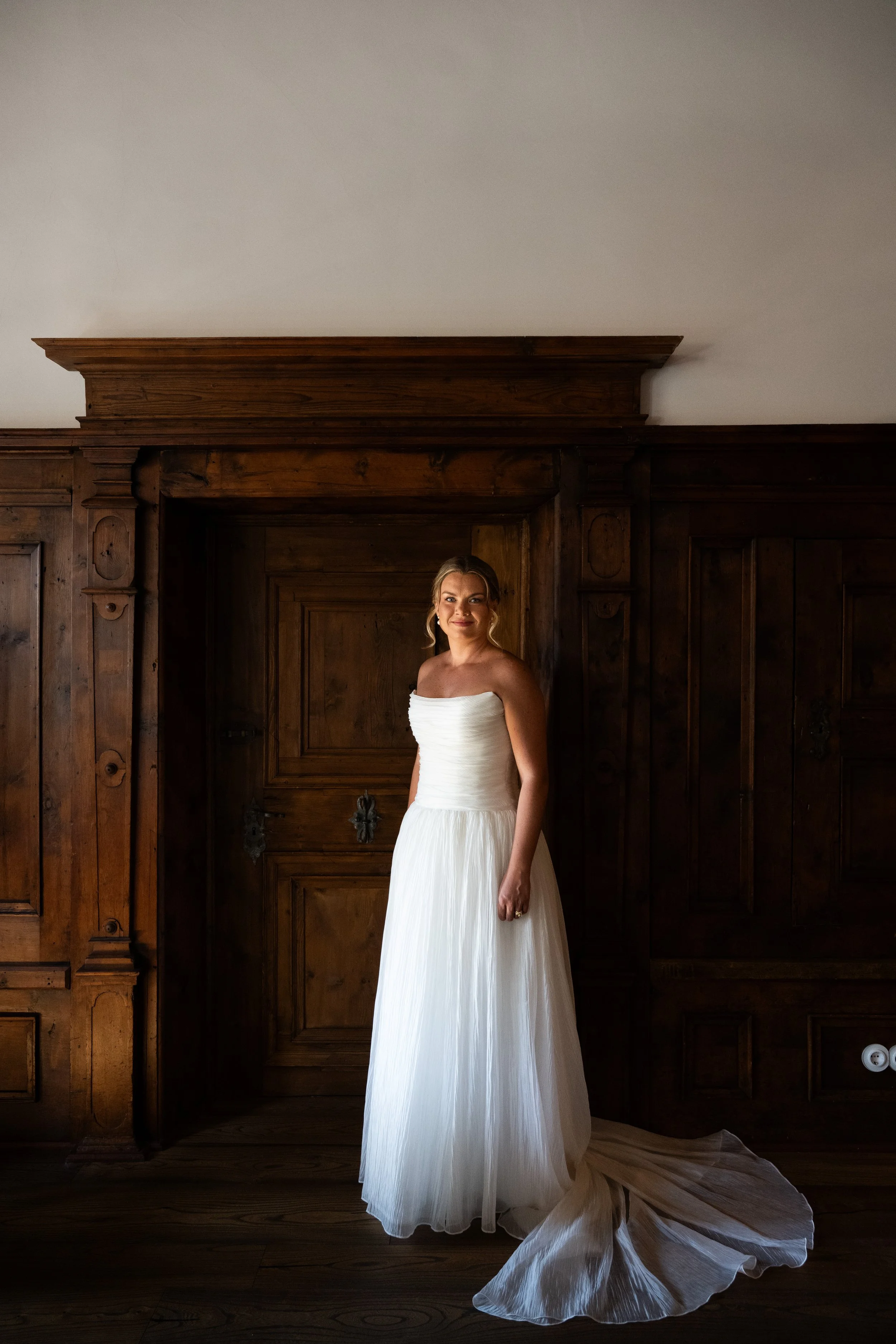  Moody, edoitorial-style bridal portrait framed by dark wood doors inside Castel Hörtenberg. 