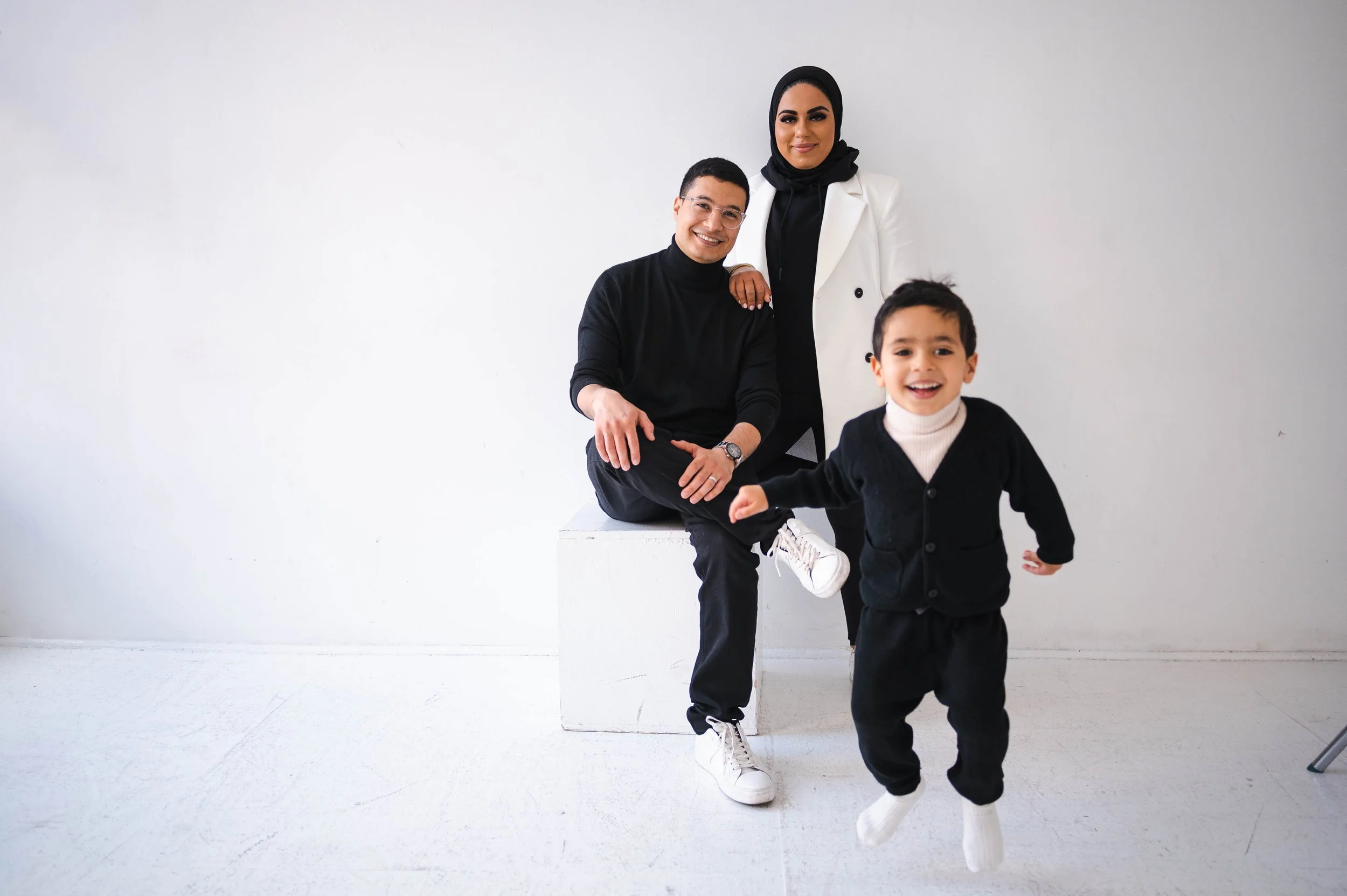 Family posing together in a studio with their child excitedly jumping during a New York City family photo session