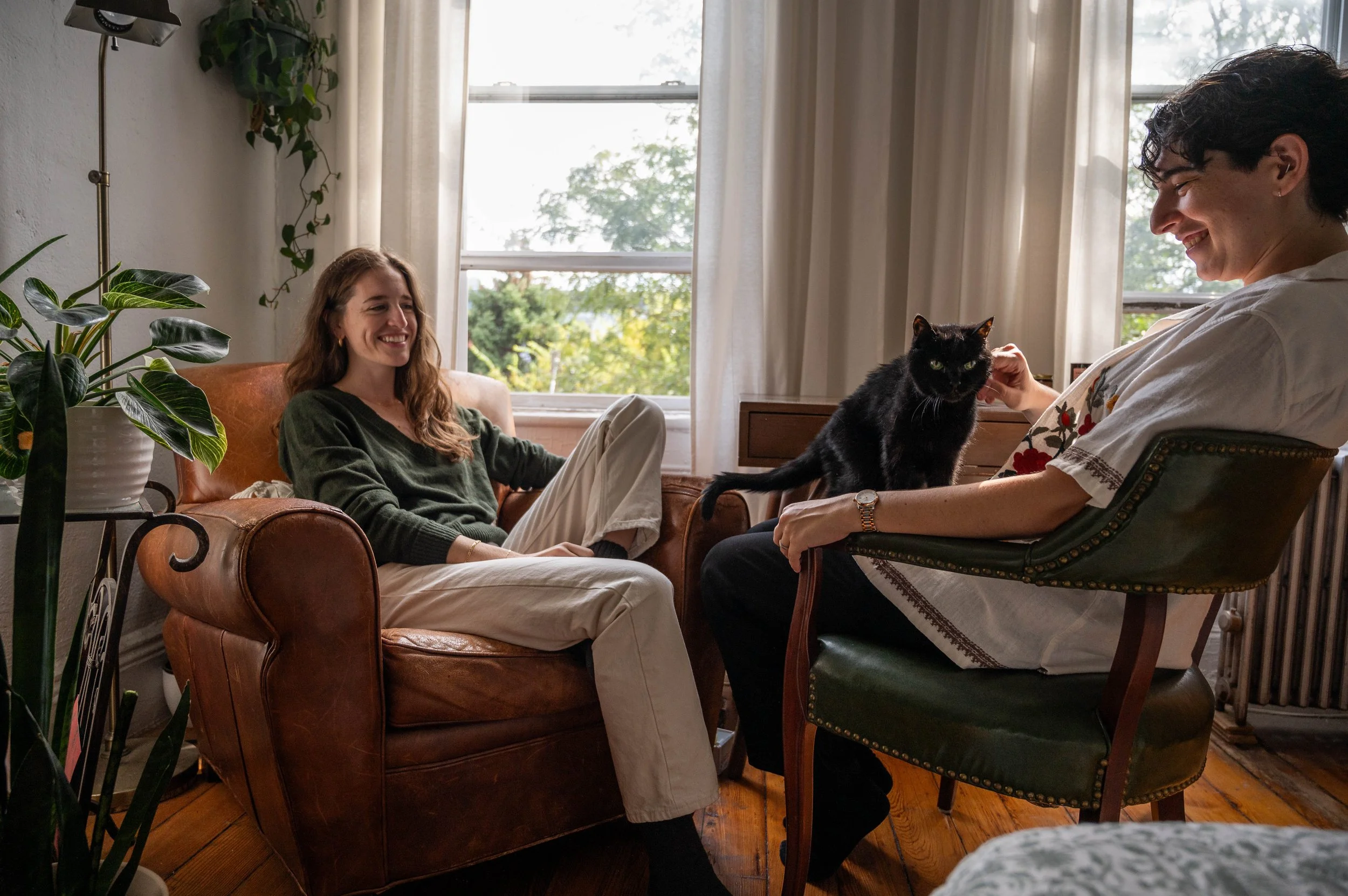 candid moment between a couple and their cat in their brooklyn apartment during an engagement photoshoot