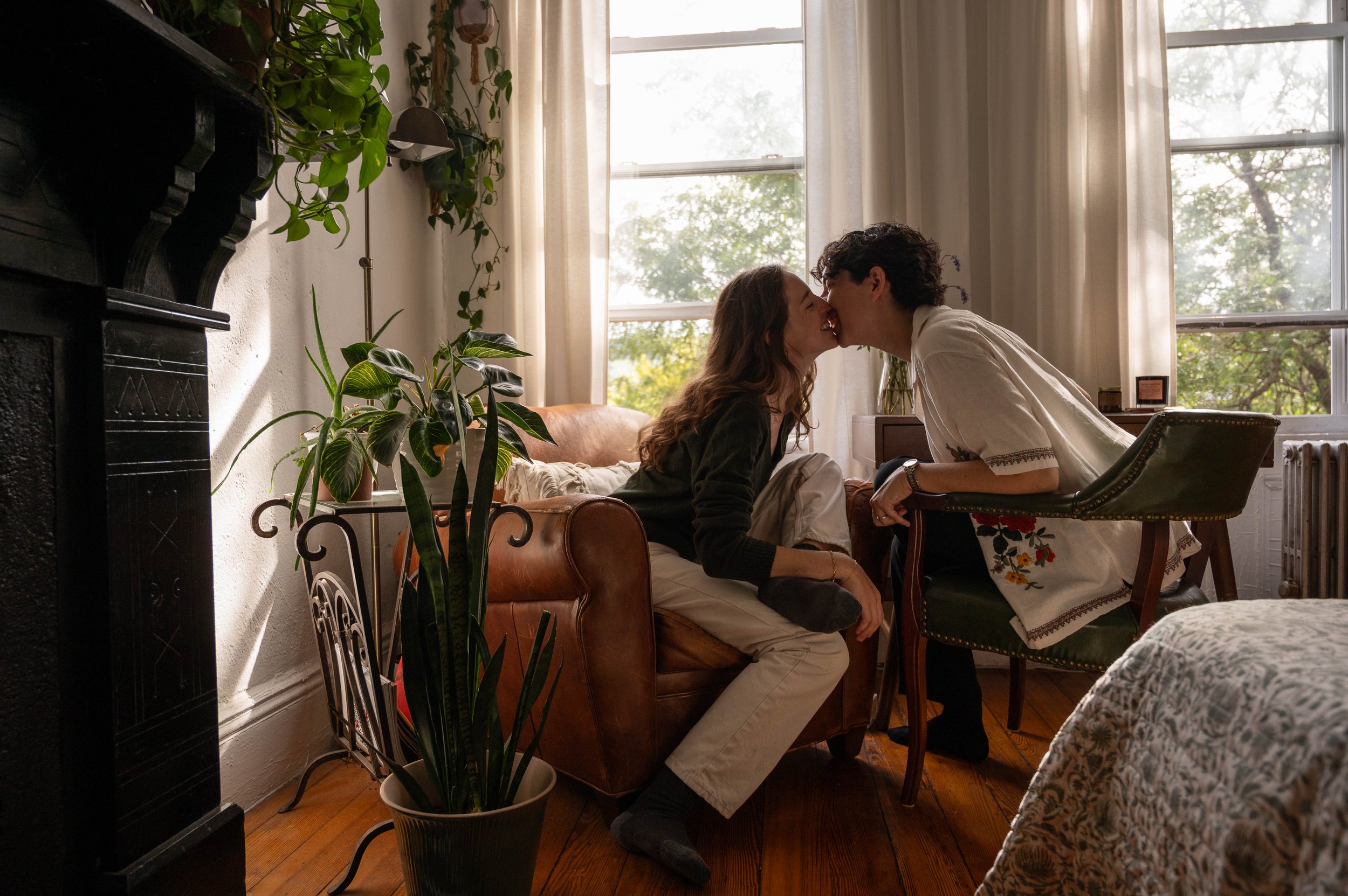 Queer couple sharing a kiss in their Brooklyn apartment during an at-home engagement photoshoot
