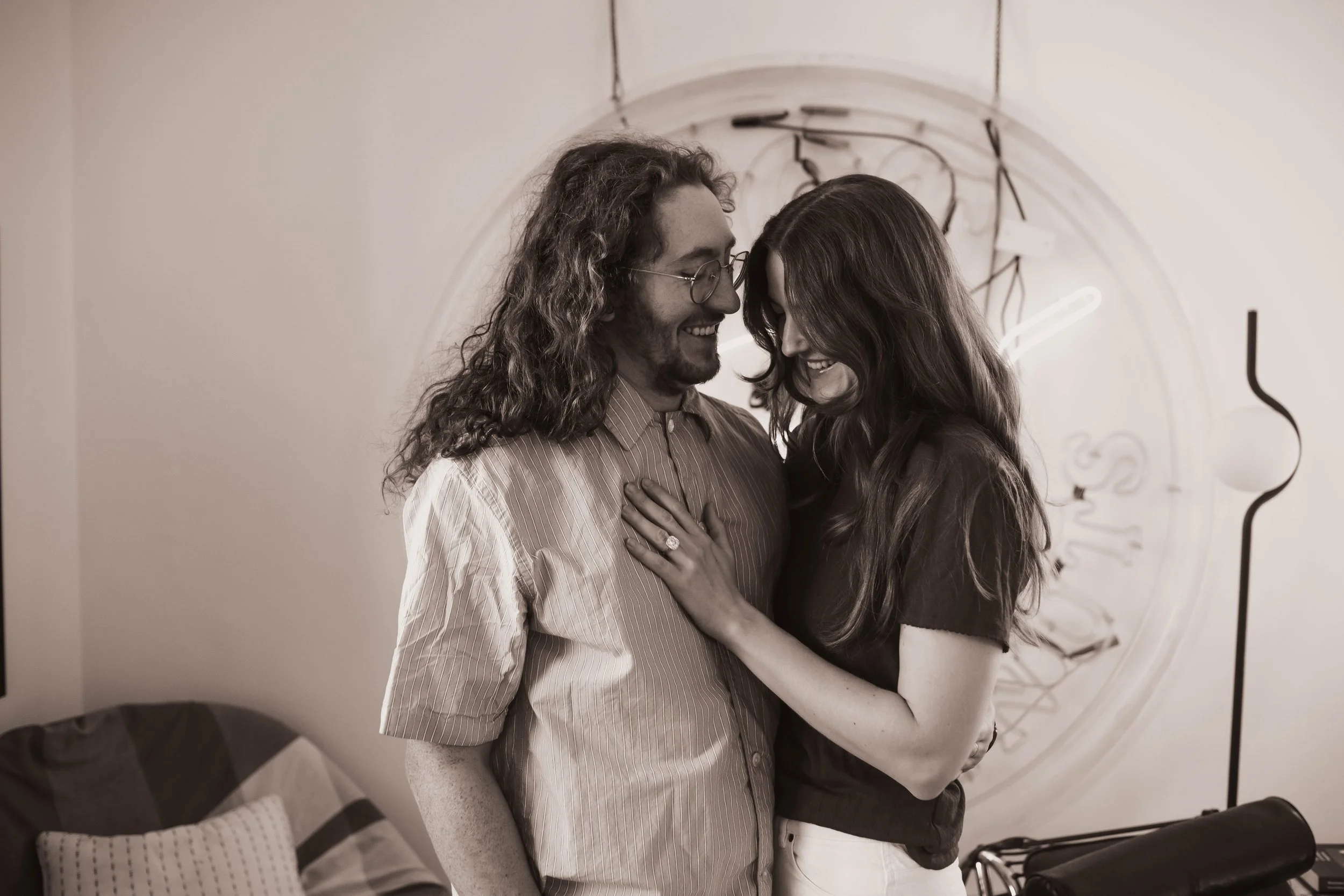 Candid tender moment of a couple embracing in their living room during an at-home Brooklyn engagement session
