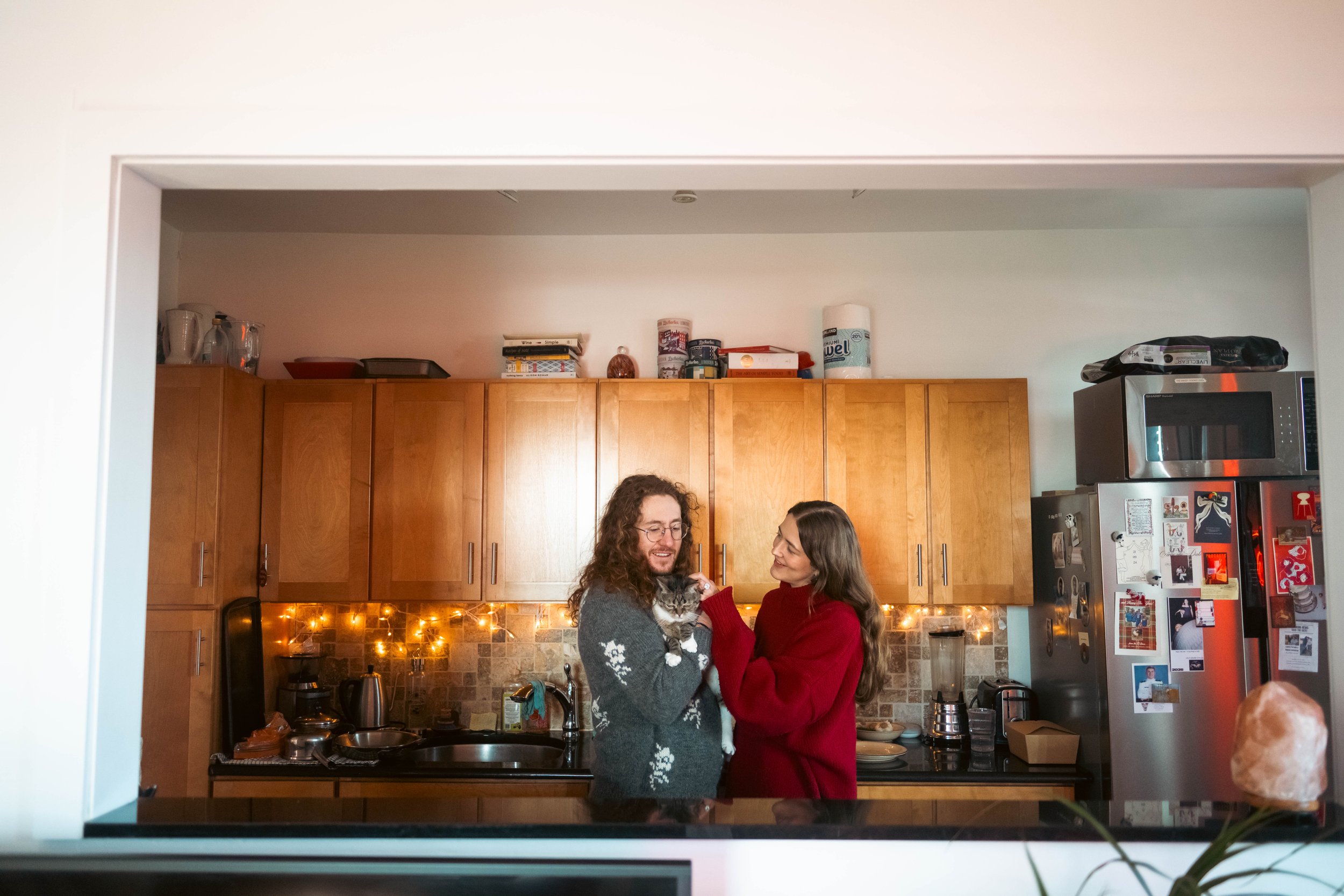 Candid photo of a couple in their kitchen with their cat during an at-home engagement session in Brooklyn, NY