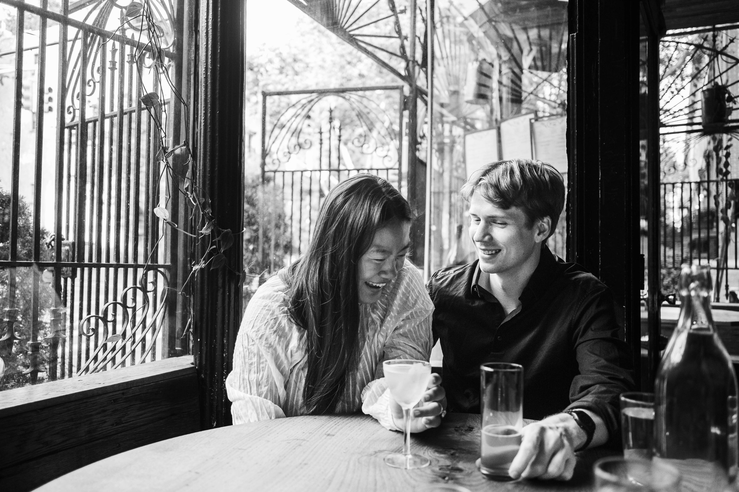 Candid photo of a couple laughing during an engagement session at a Brooklyn restaurant