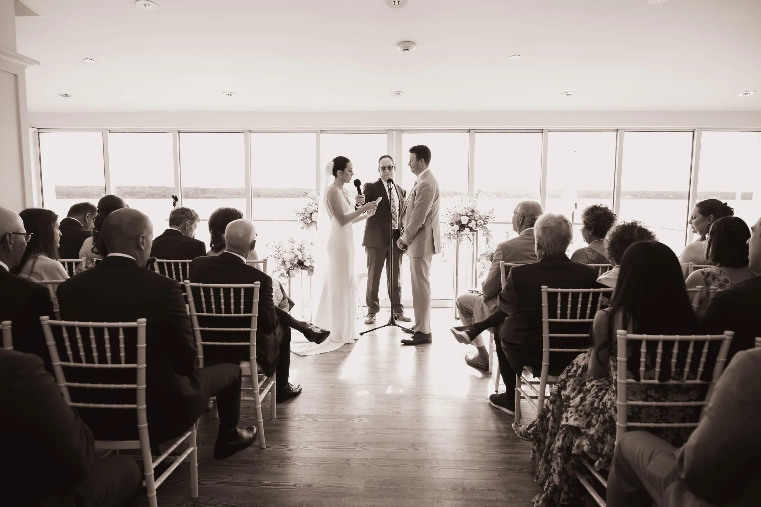 A wide, documentary shot of a beautiful wedding ceremony in East Hampton, capturing the scenic landscape and guests.