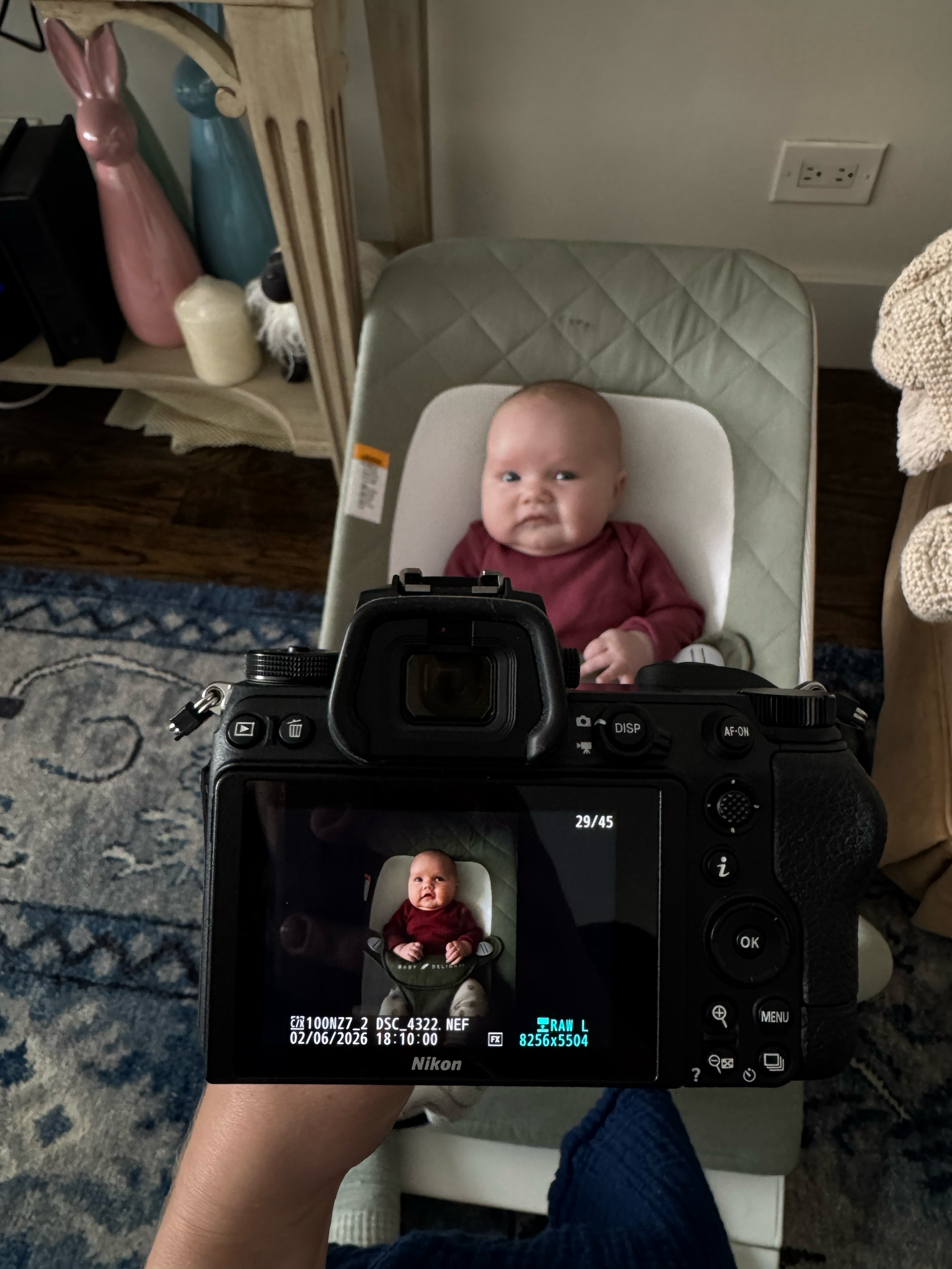 The back of a digital camera screen displaying a captured photograph of a baby daughter, professional photography process.