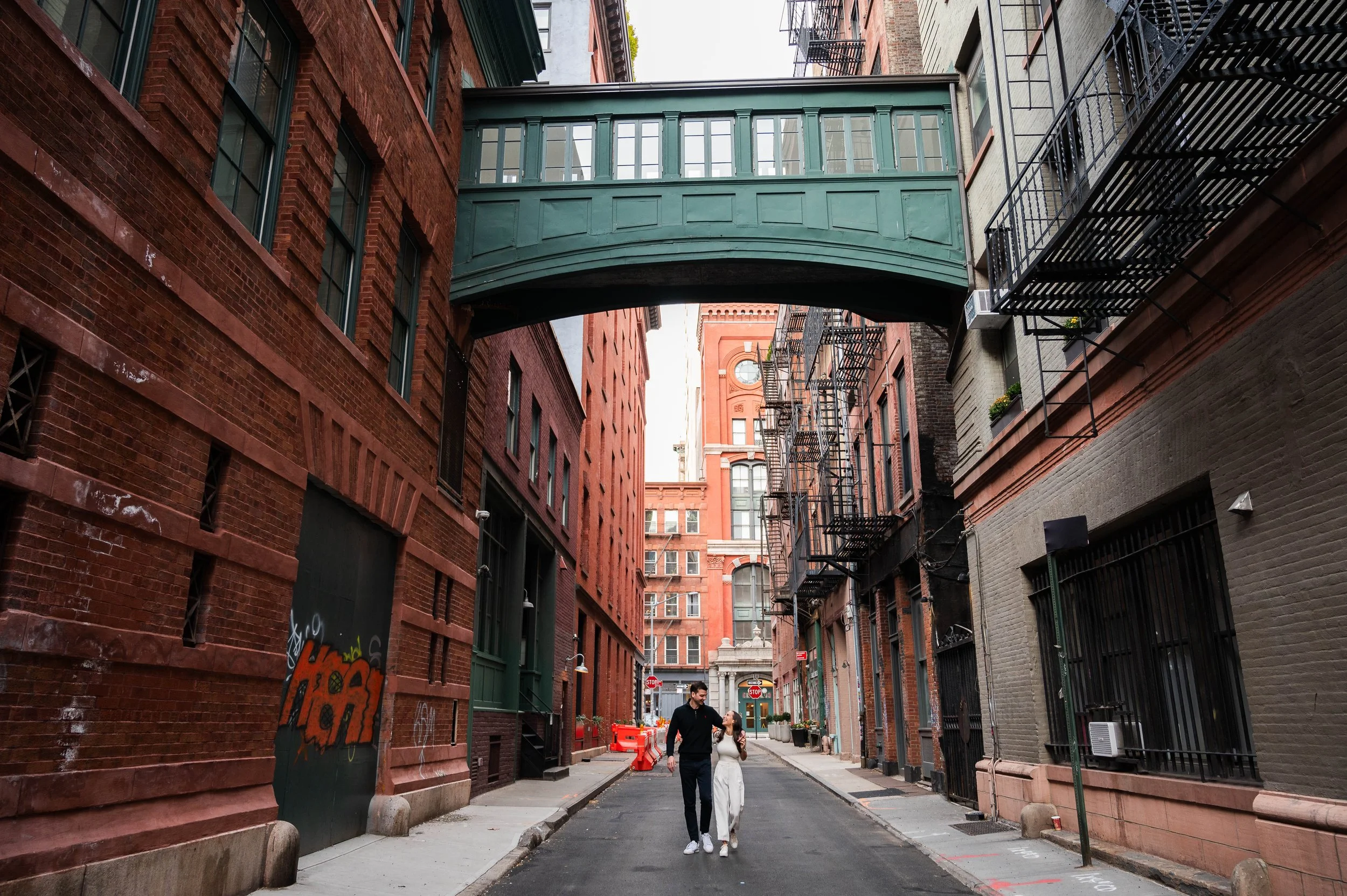 Candid photo of a couple walking in TriBeCa under the iconic Staple Street Skybridge