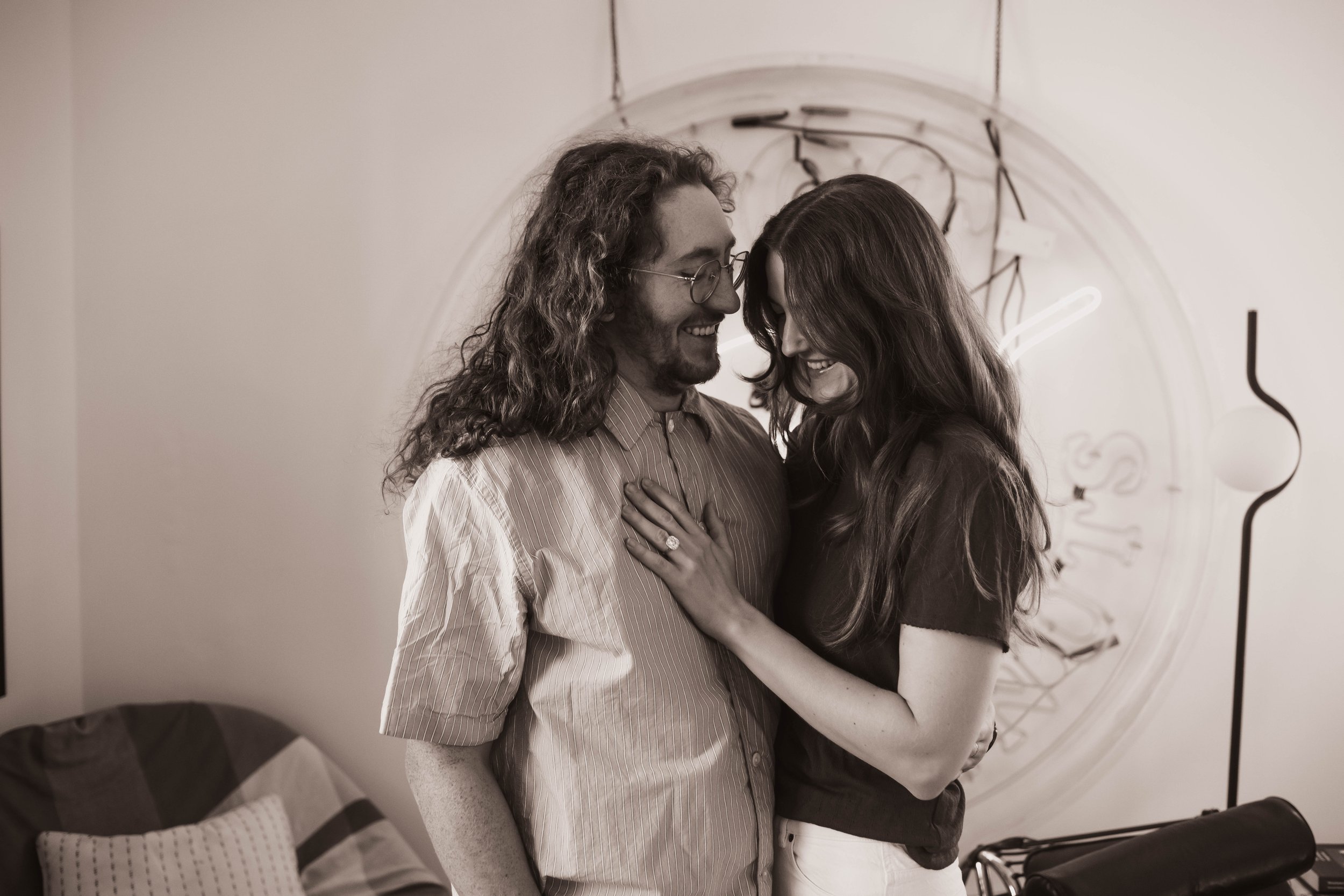 Candid tender moment of a couple embracing in their living room during an at-home Brooklyn engagement session