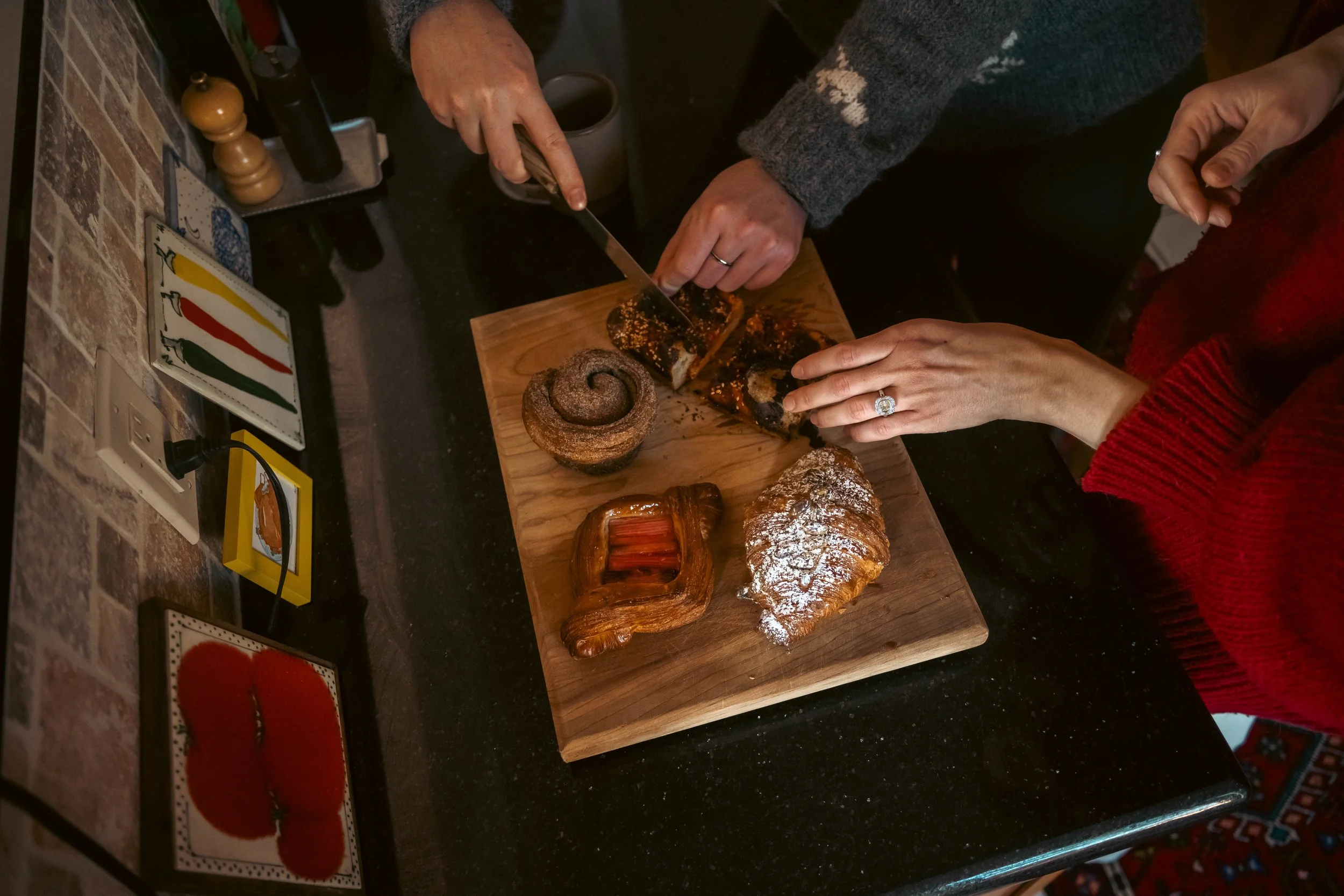 Couple cutting pastries together in their kitchen during an at-home engagement session in Crown Heights, Brooklyn