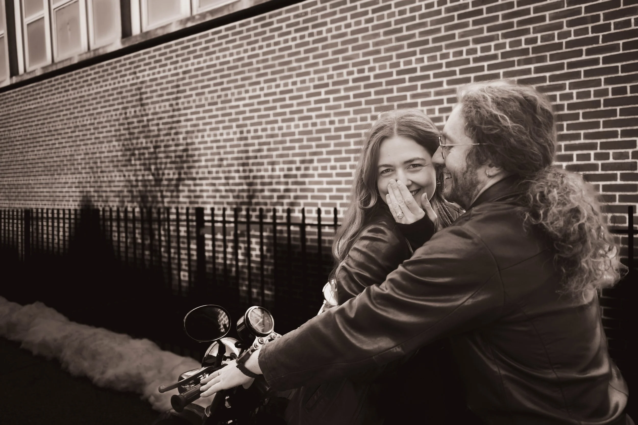 Couple on their motorcycle on a Brooklyn block during an outdoor engagement session in Crown Heights, NY