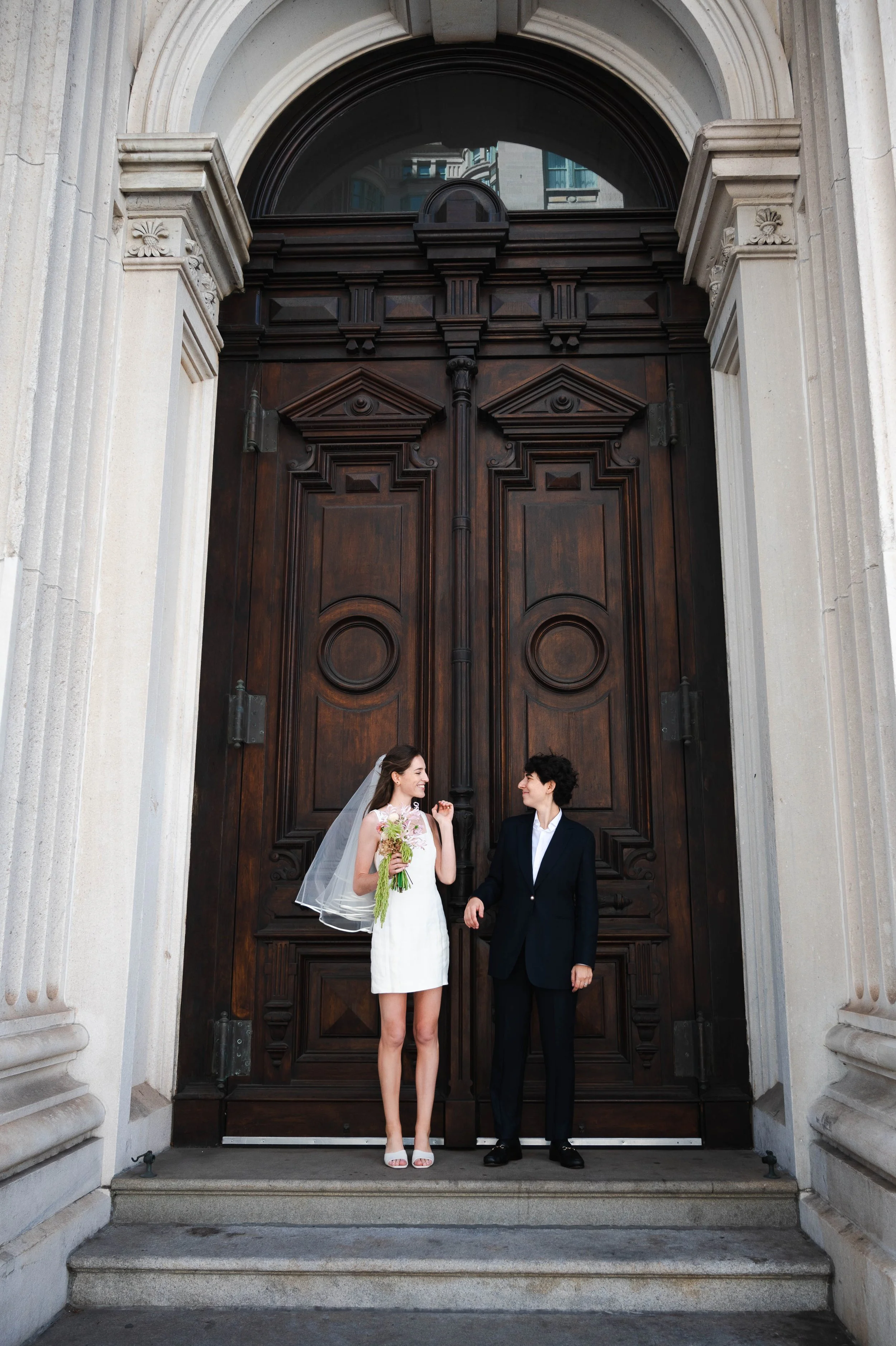 Queer couple smiling outside after their City Hall wedding in New York City