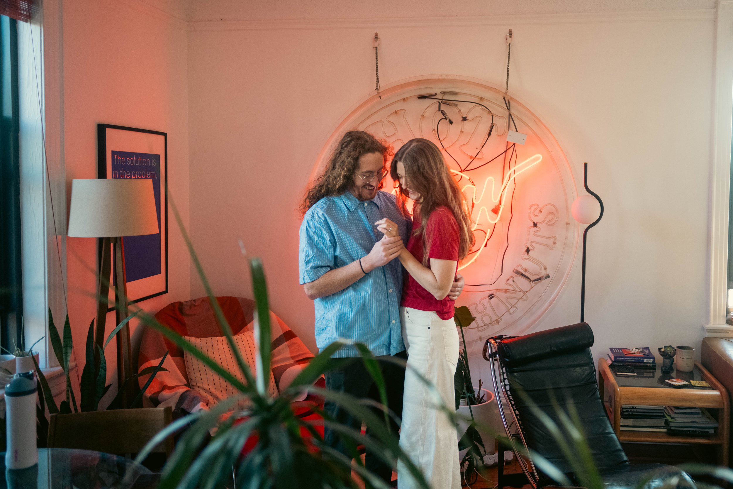 Couple dances in living room during  engagement photoshoot at home