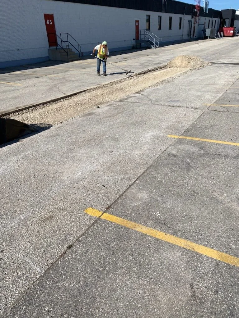 Construction worker smoothing asphalt in a parking lot.