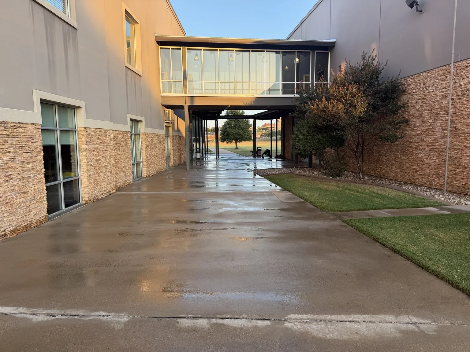 After: courtyard cleaned by 76 Surface Care, with water still visible as the concrete dries.