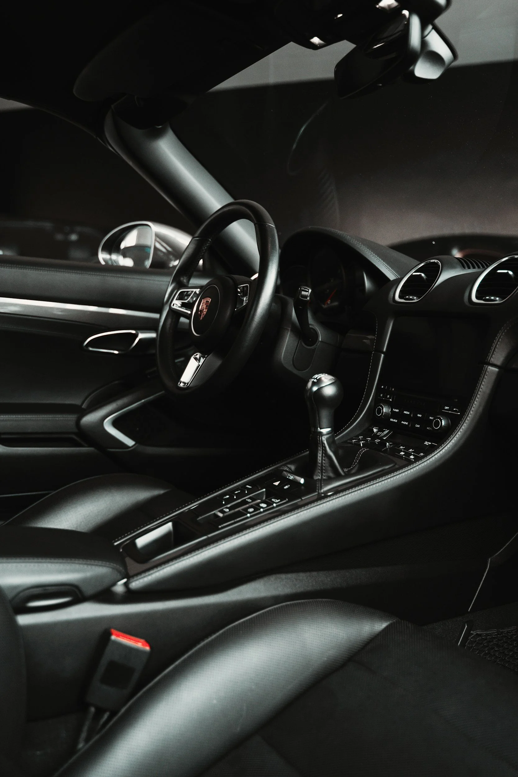 Interior of a black sports car, focusing on the steering wheel, gear shift, and dashboard.