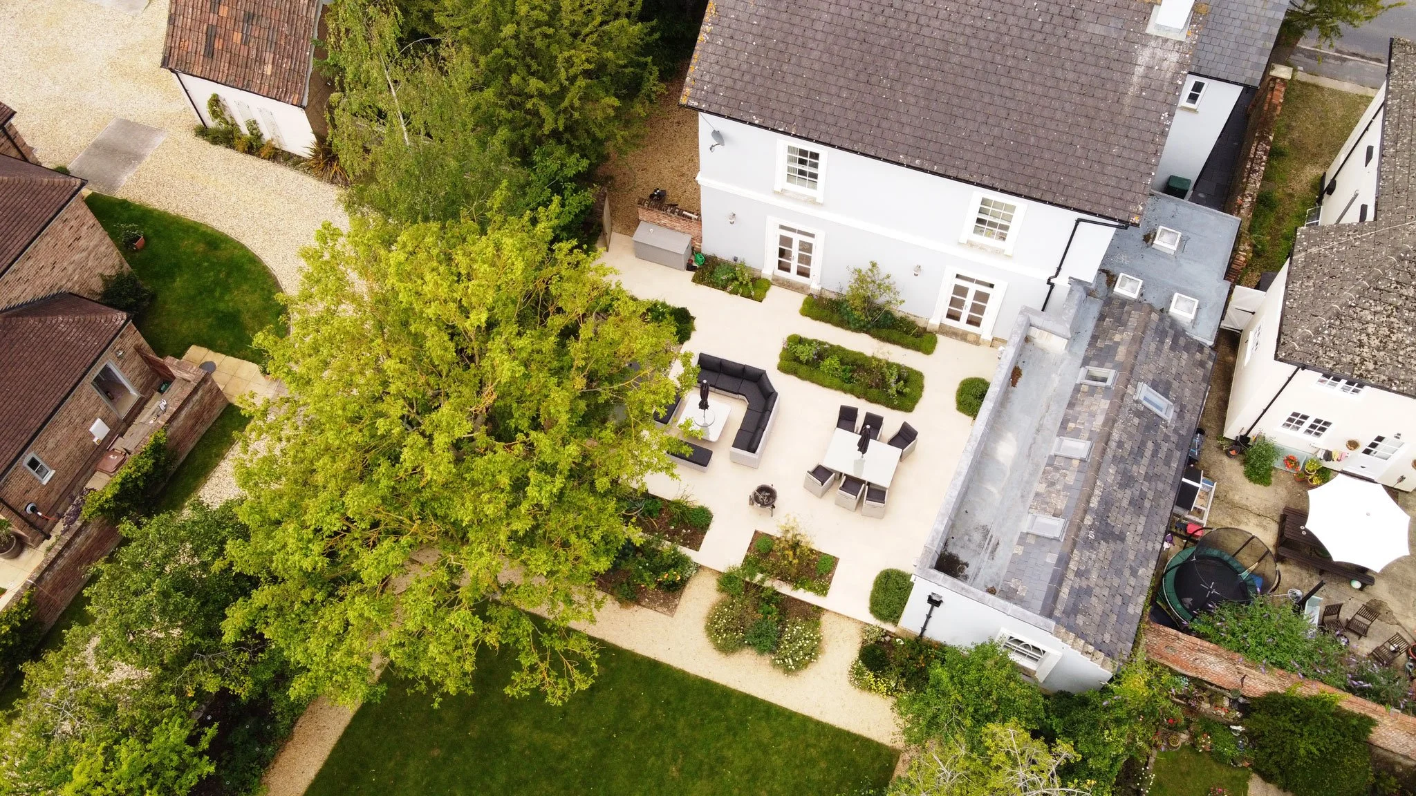 Aerial view of a walled garden with lawn, paved terraces and mature trees in Faringdon, Oxfordshire.