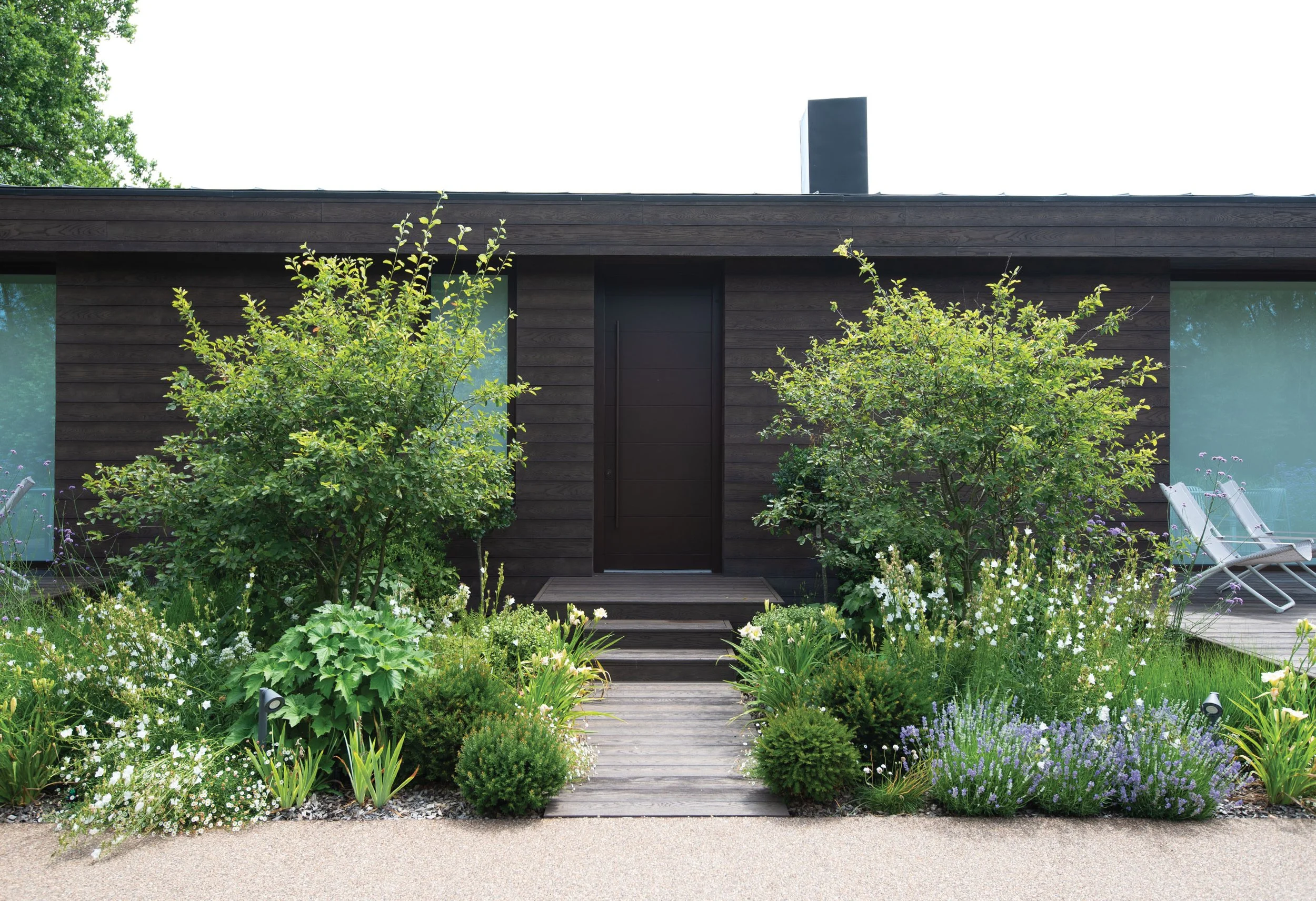 Entrance to The Fishing Lodge framed by Amelanchier trees, perennial planting and a timber boardwalk.