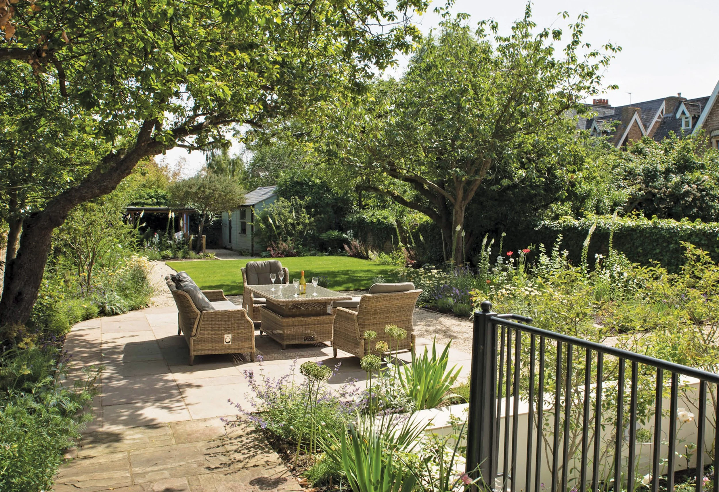 Garden terrace beneath mature fruit trees, with informal seating and flowering planting around the lawn.