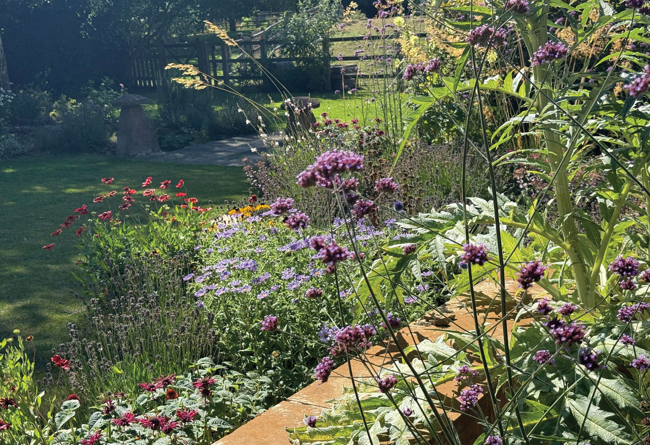 Colourful perennial planting creating a loose, naturalistic contrast with the formal brick walls of the courtyard.