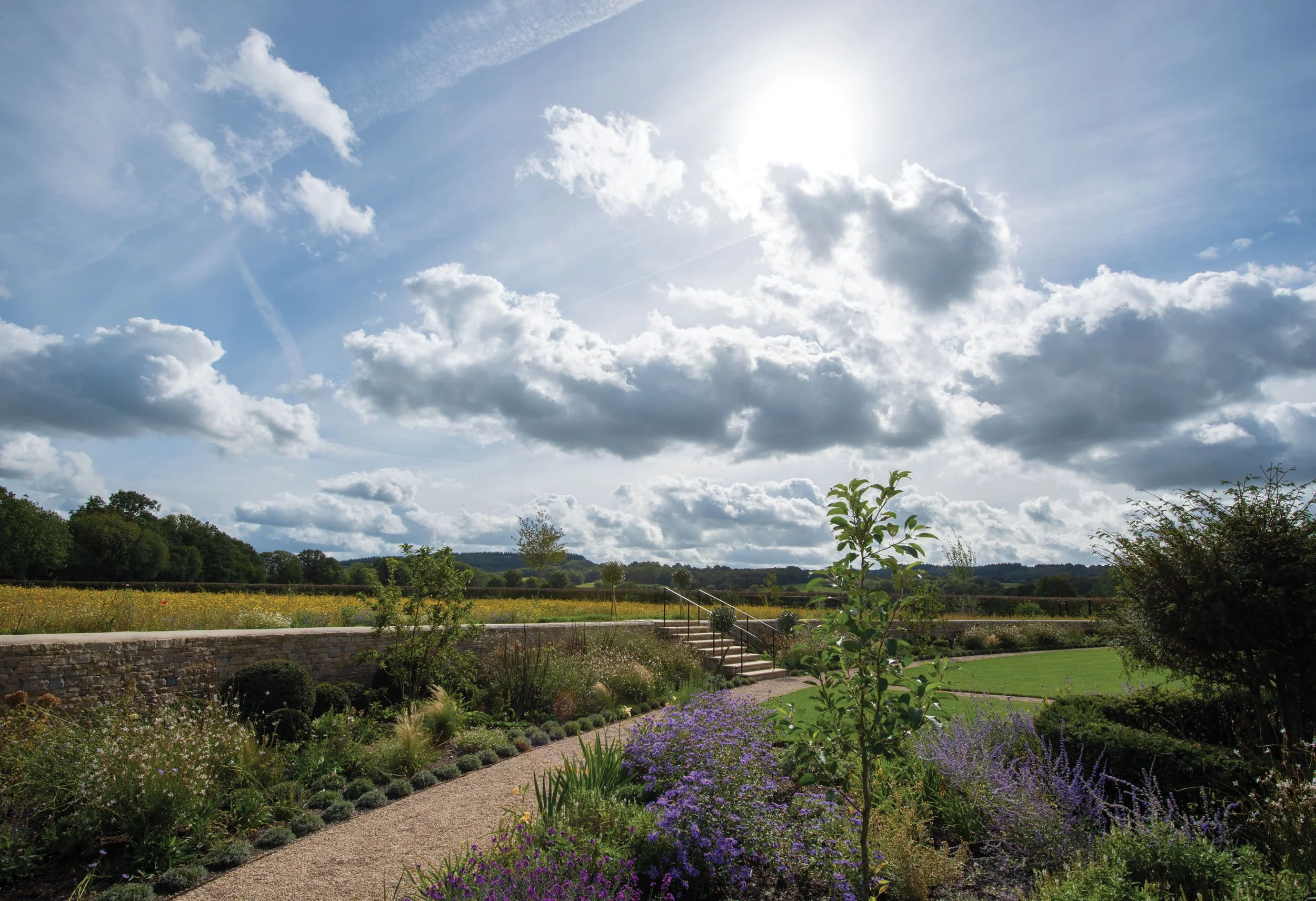 Garden path and sculptural dry stone wall moving through naturalistic planting towards the meadow and wider countryside.